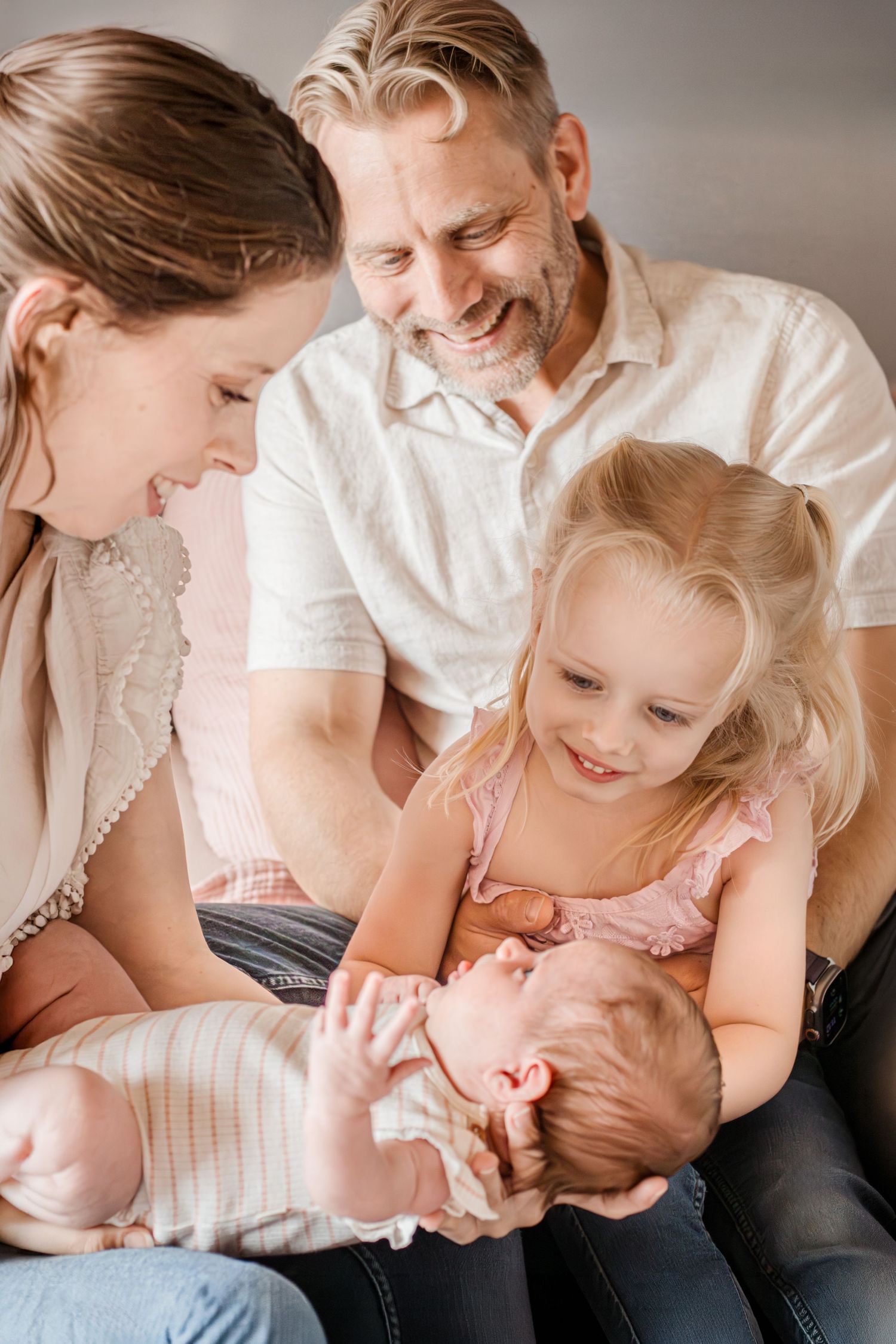 Gezinnetje dat liefdevol kijkt naar het pasgeboren gezinslid tijdens een newbornshoot in Zuid-Holland.