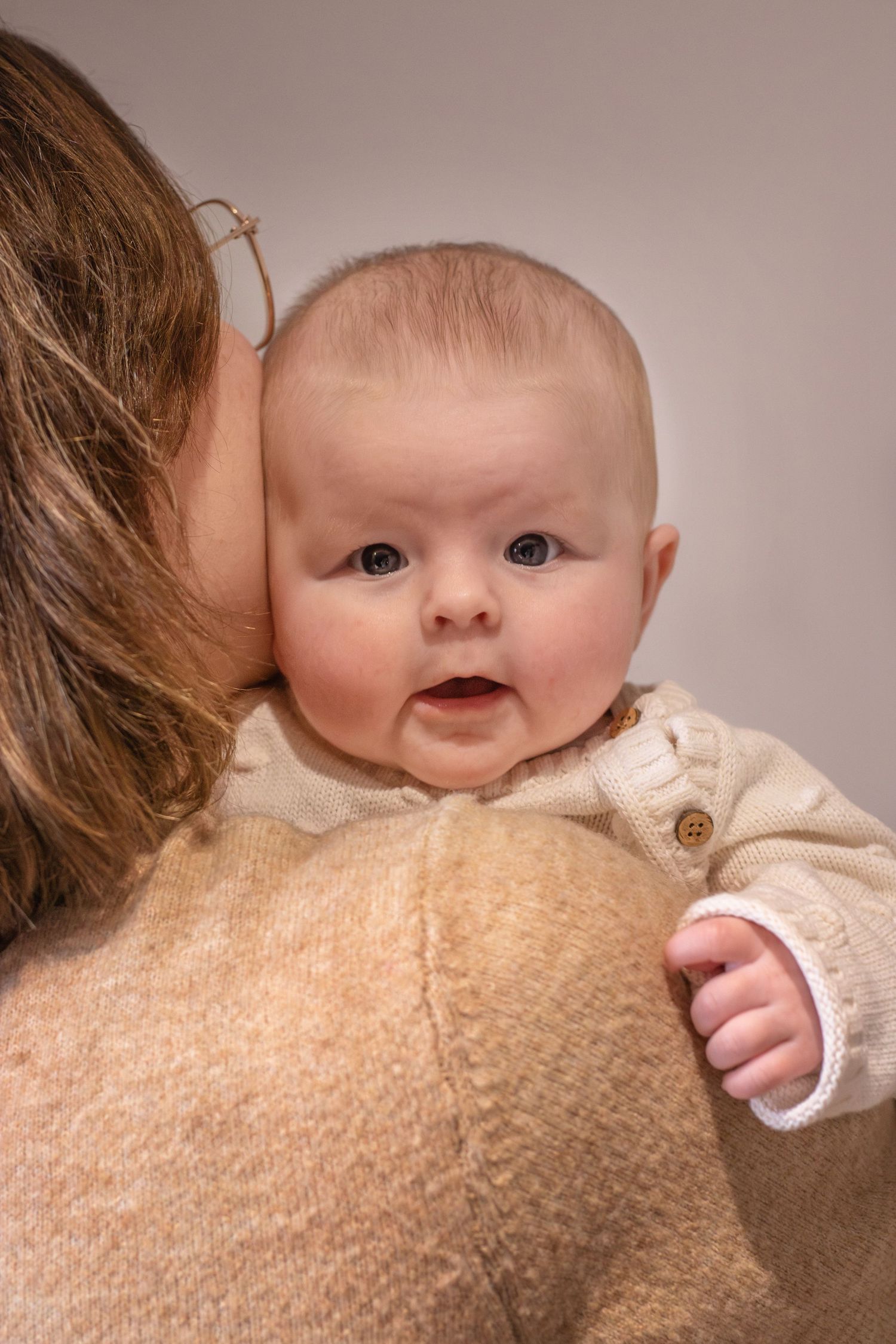 Pasgeboren baby in de armen van mama lachend tijdens een newbornshoot in Zuid-Holland.