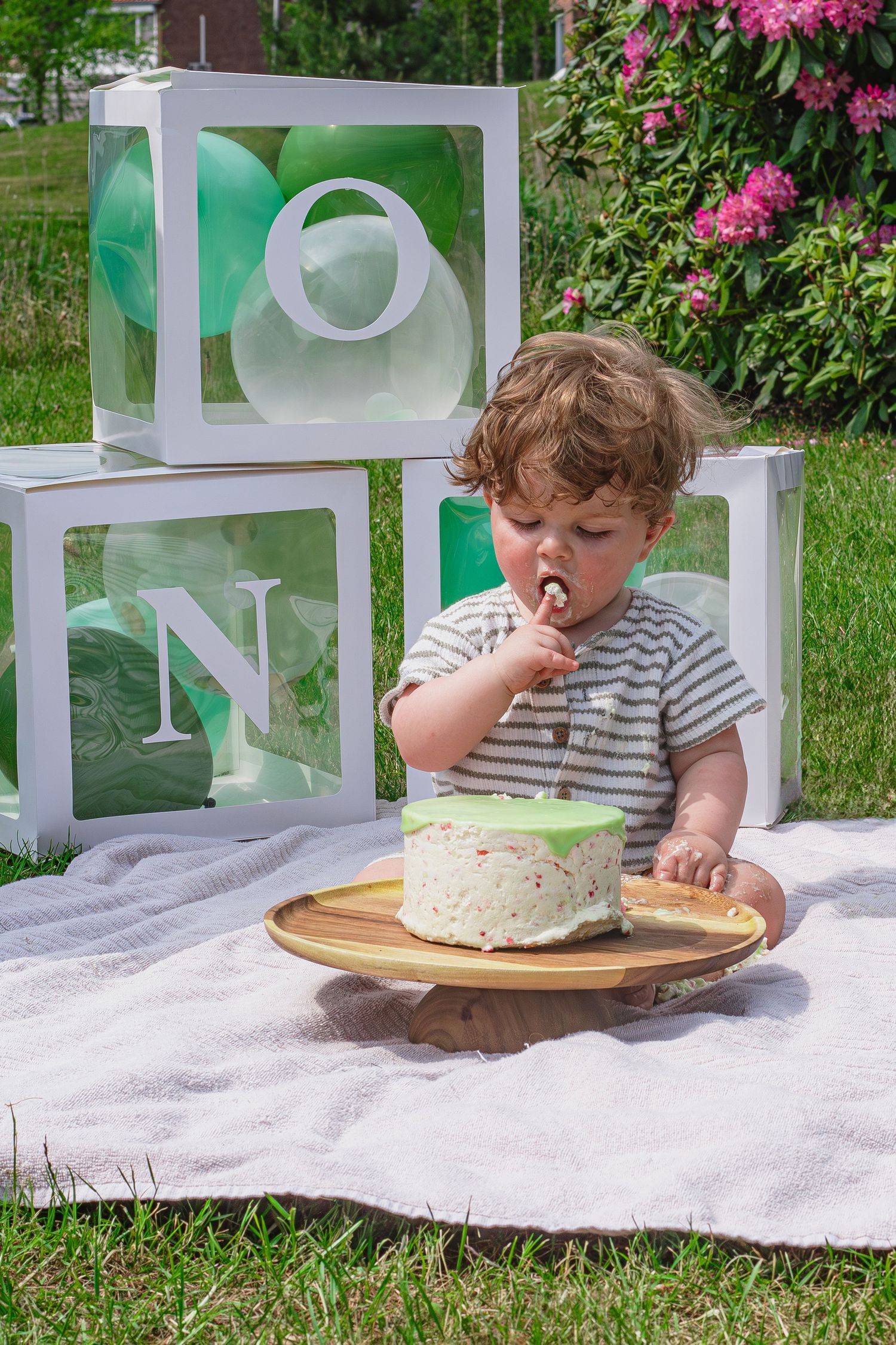 Baby met zijn vingers eten van de taart tijdens een cakesmashshoot in Breda.