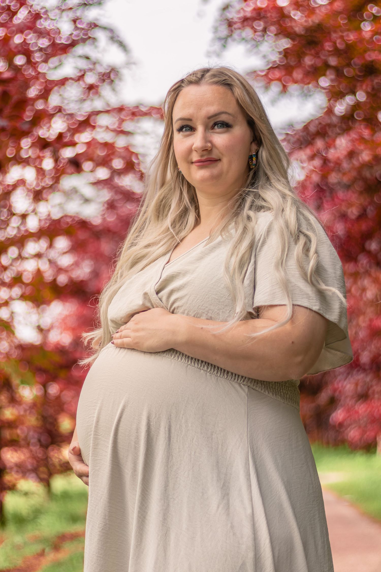 Zwangere vrouw in bos bij rode bomen tijdens een zwangerschapshoot in Zuid-Holland.