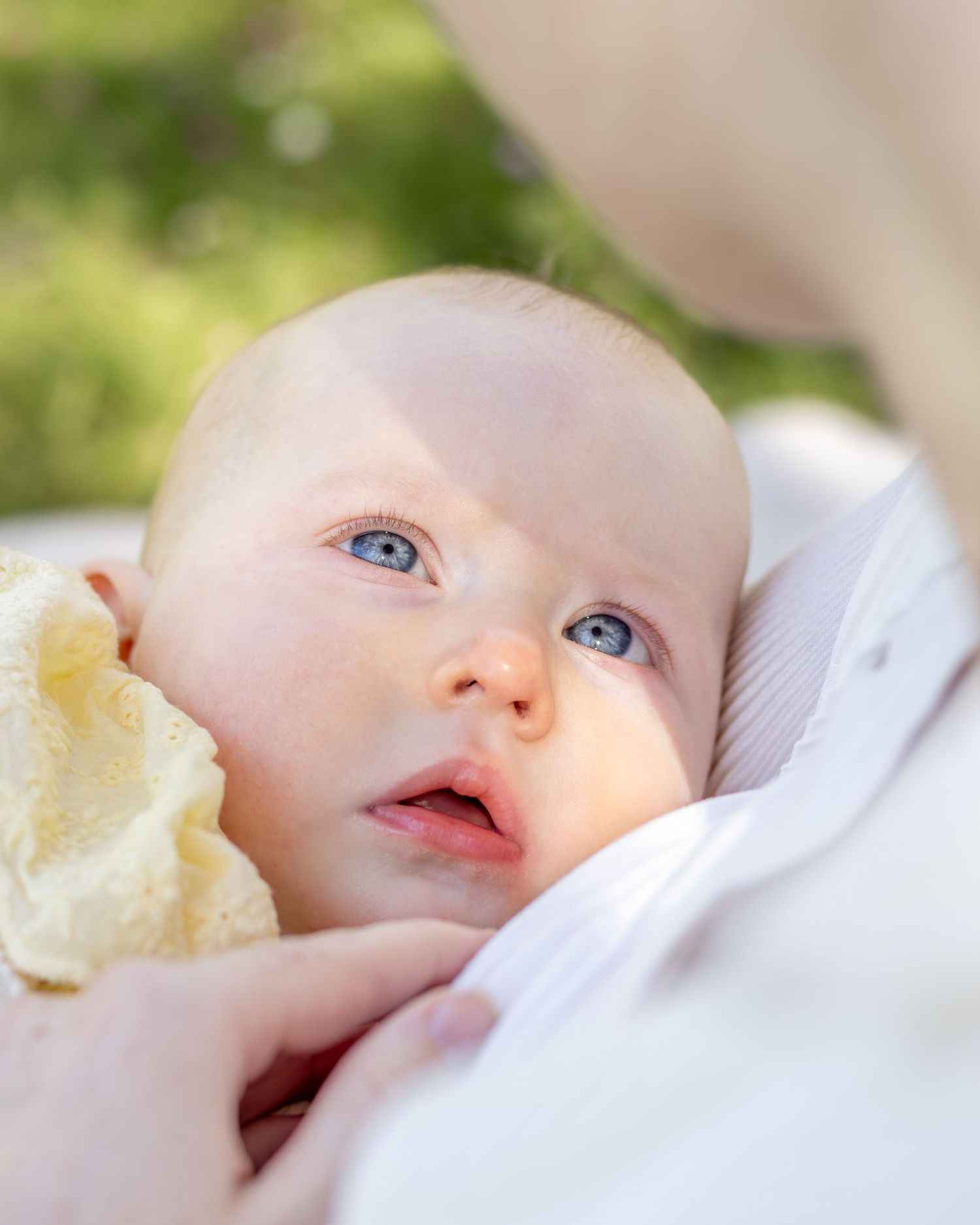 Baby met blauwen ogen vol verwondering kijkend naar mama tijdens een Moeder & Doctershoot in Zuid-Holland.