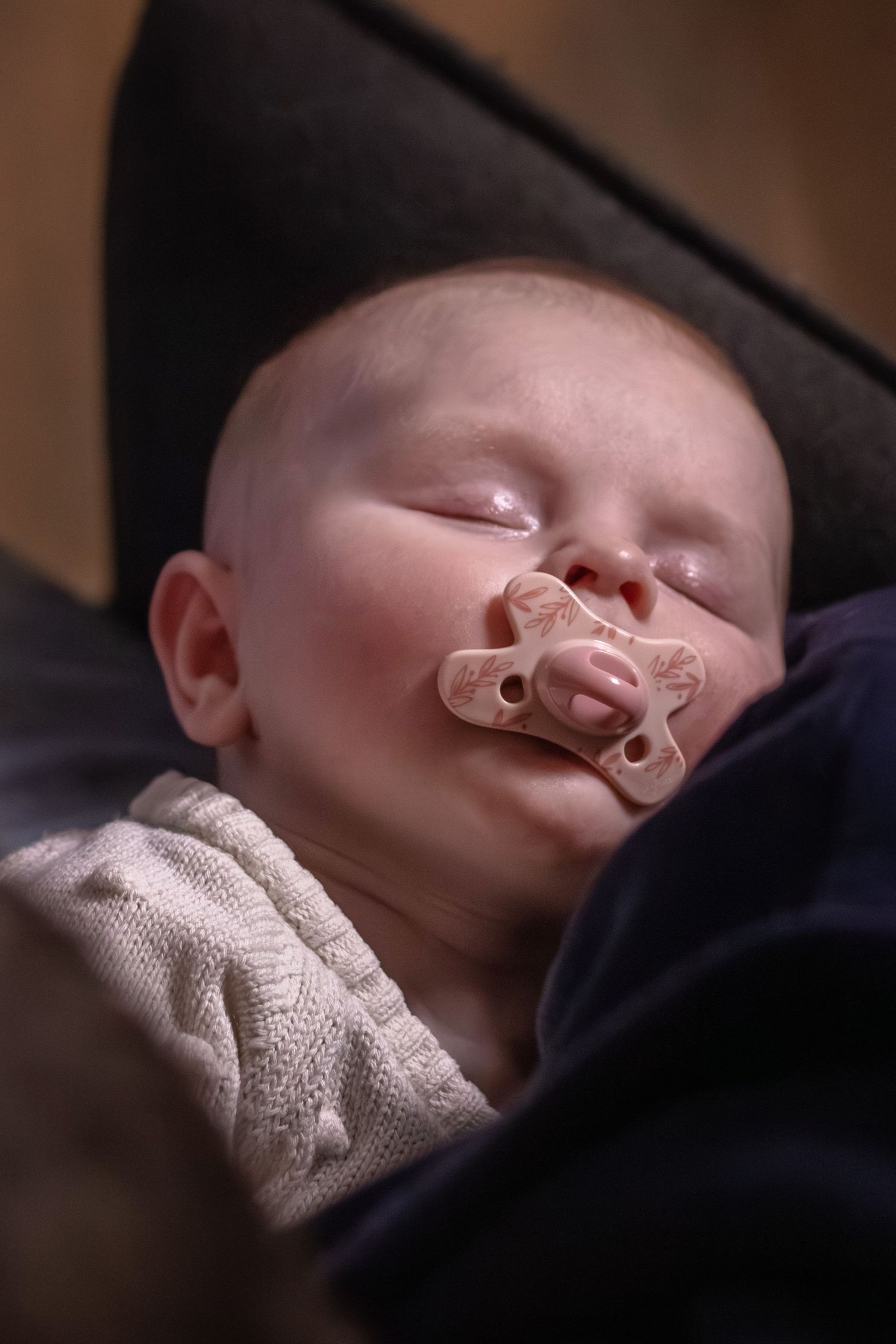 Pasgeboren baby slapend op papa zijn schoot tijdens een newbornshoot in Zuid-Holland.
