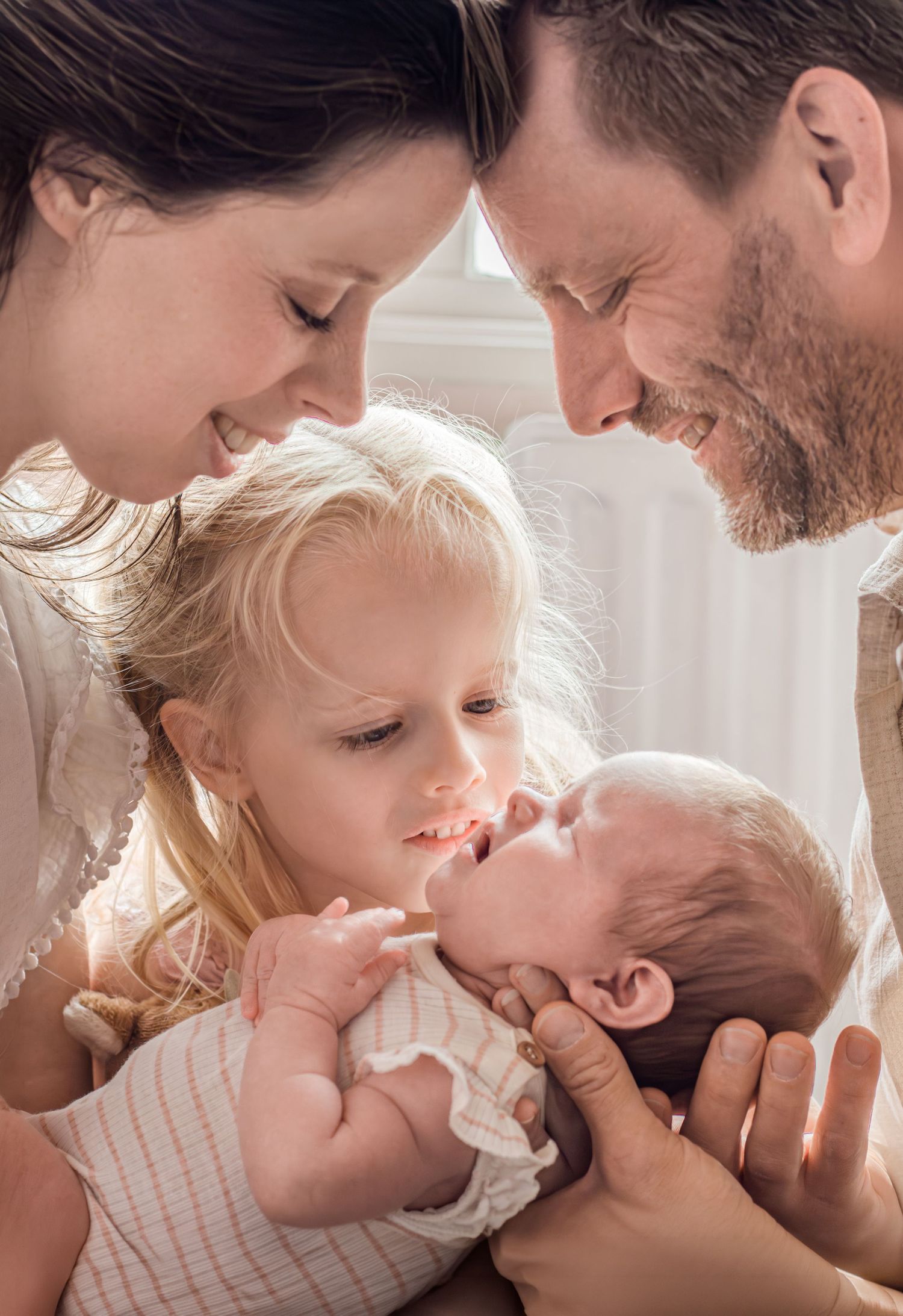 Gezinnetje samen vol liefde kijkend naar de pasgeboren baby tijdens een newbornshoot in Zuid-Holland.