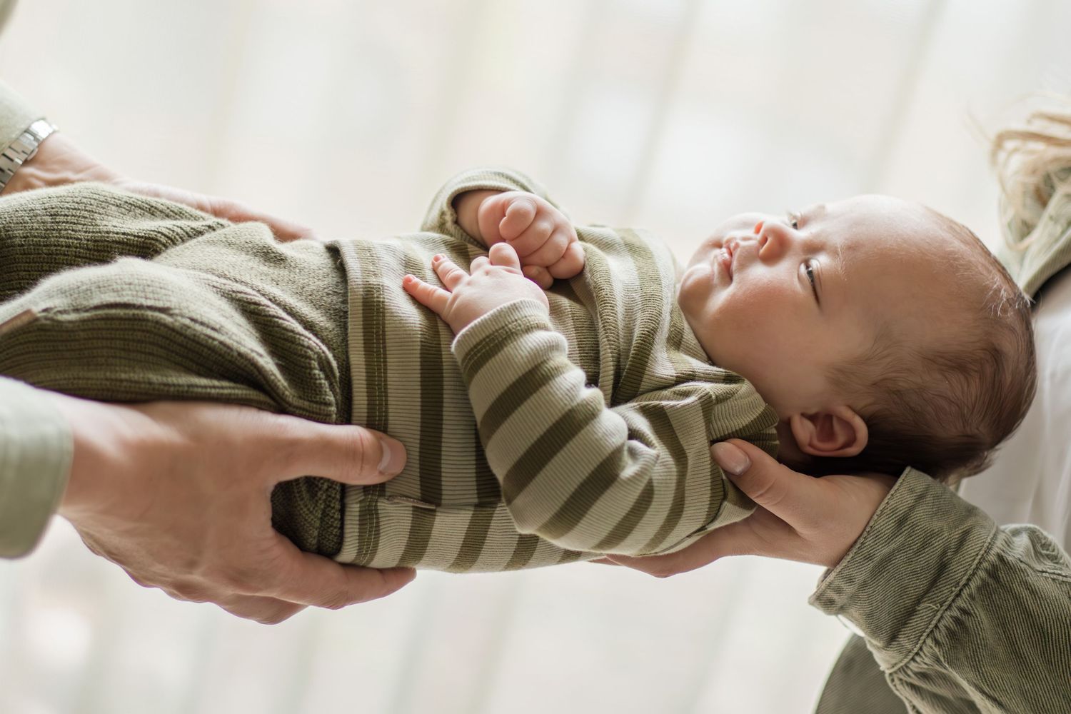 Newborn en armen van ouders slapend tijdens een newbornshoot in Zuid-Holland.