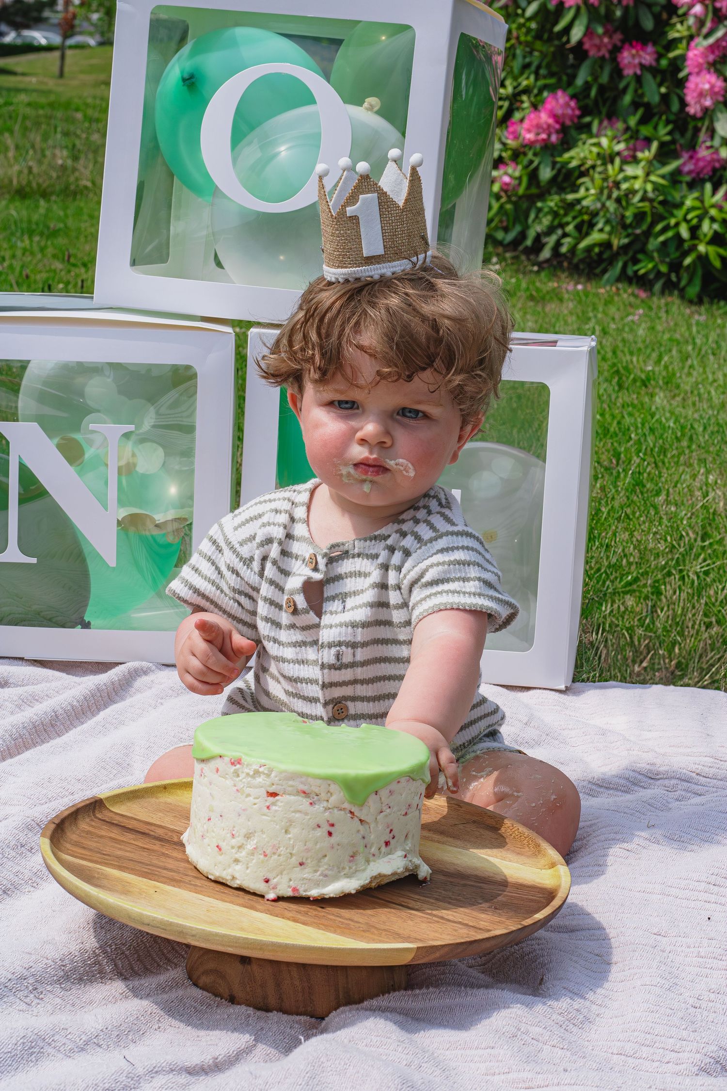 Baby zitten op kleed met een één jaar kroontje eten van zijn taart tijdens een cakesmashshoot in Breda.