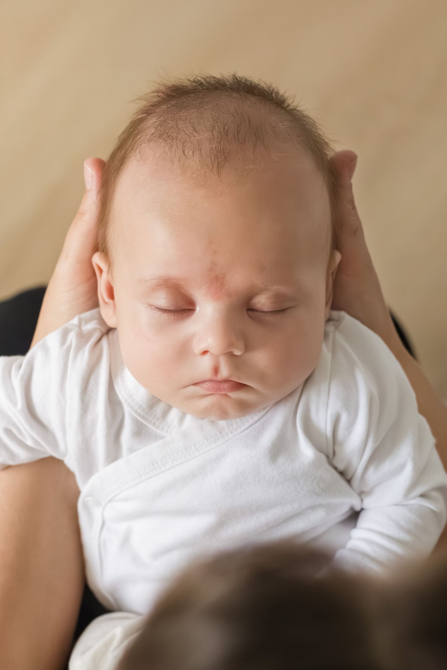 Baby slapend in armen van moeder tijdens een newbornshoot in Zuid-Holland.
