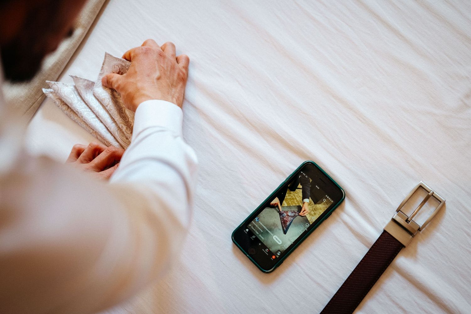 Le marié regarde une vidéo pendant les préparatifs pour bien faire le pli de son mouchoir