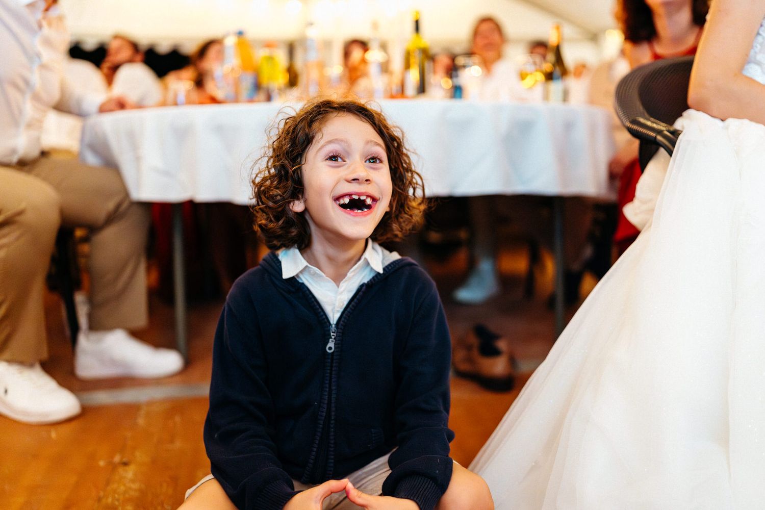 Enfant avec un grand sourire de suprise pendant une réception de mariage au moment du repas