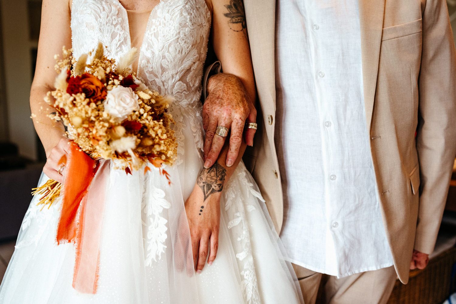 Mariée et son père photo au cadrage très sérré sur les mains et le bouquet de la mariée