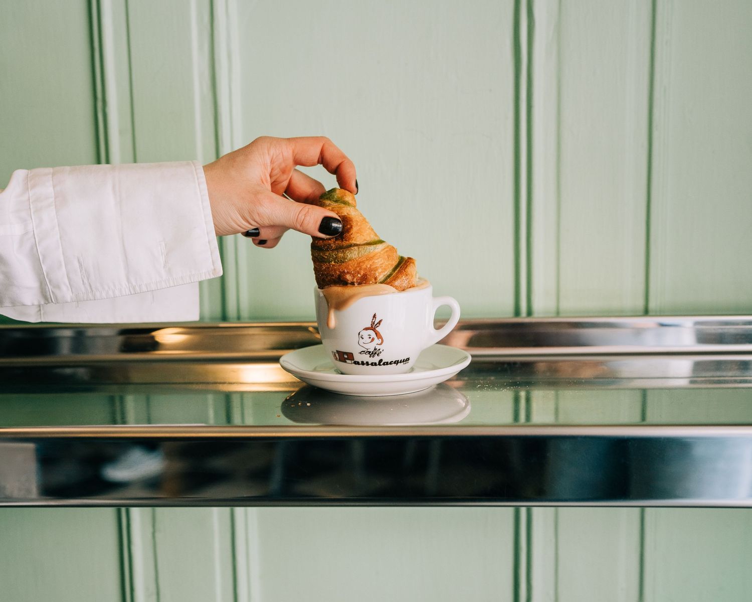 Italian croissant bring dipped into authentic Italian coffee at a cafe in Stockholm for commercial photography