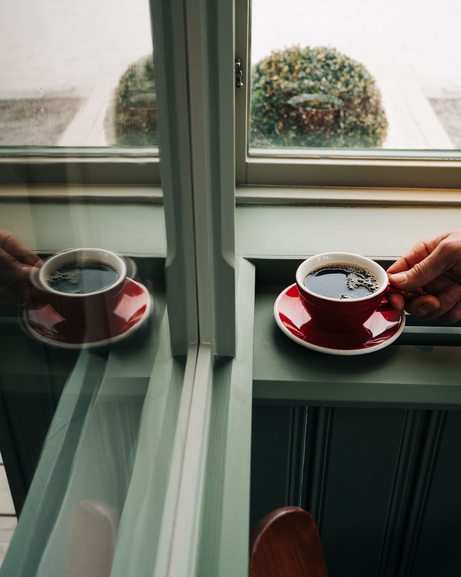 cup of coffee with a hand by a window in a cafe in Stockholm, Sweden. En kopp kaffe med en hand vid ett fönster på ett café i Stockholm, Sve