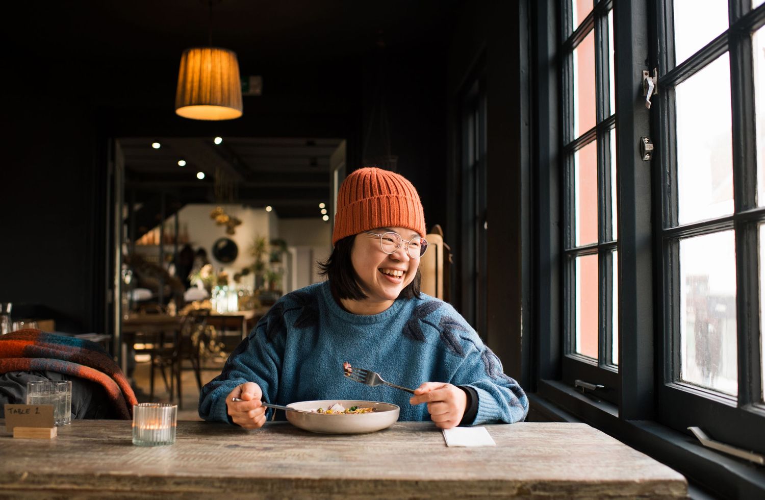 Commercial lifestyle cafe and restaurant photography woman smiling eating a salad in a restaurant in Stockholm