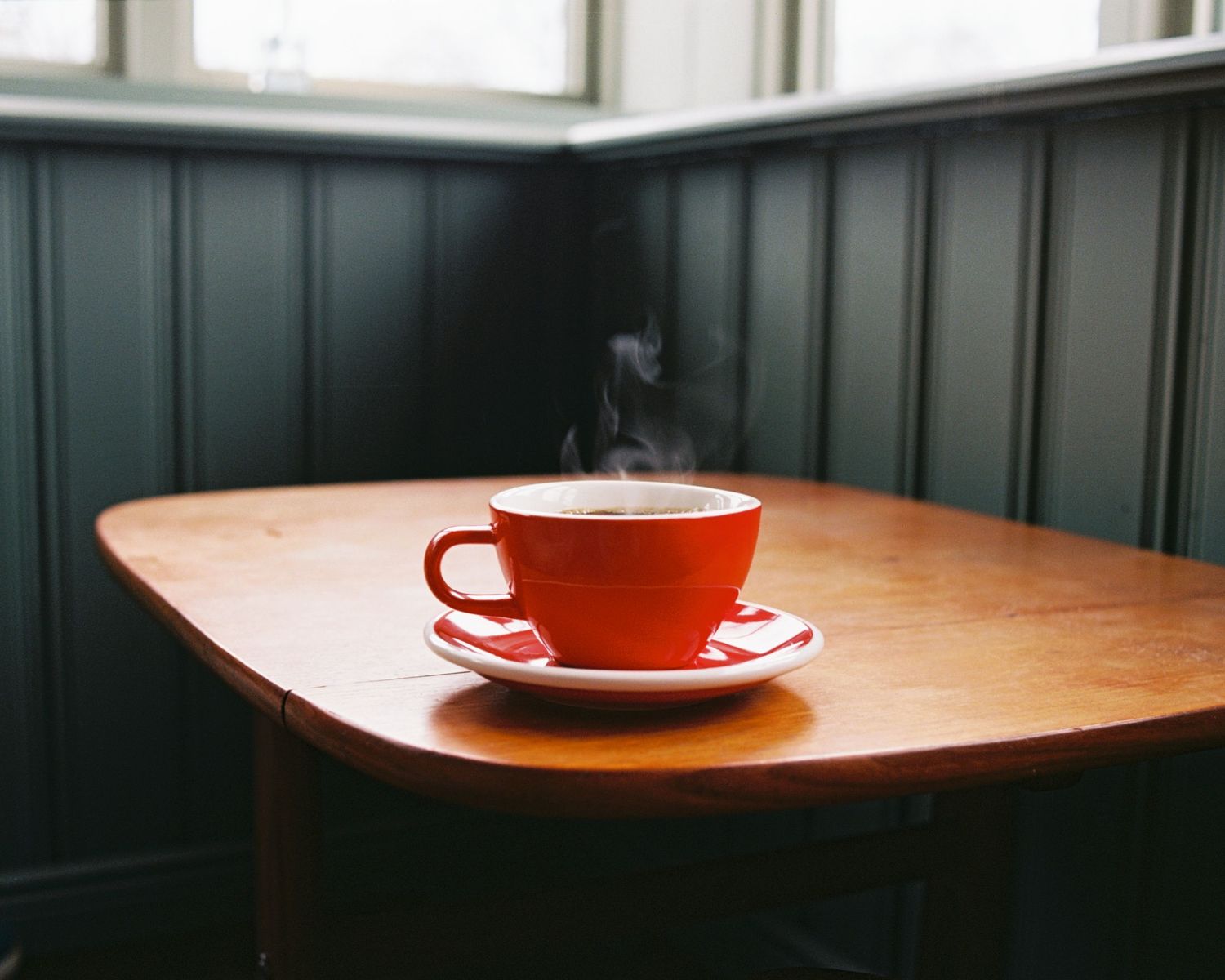 Steaming hot cup of coffee in a red mug on a table in a cafe shot on film in Stockholm