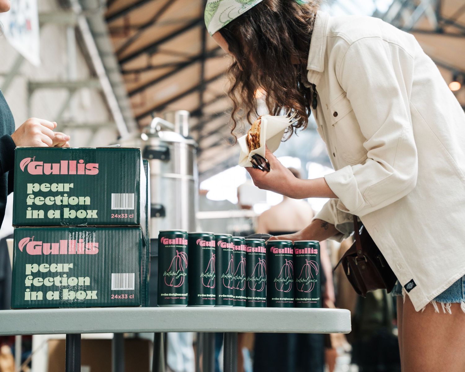 woman paying for her Gullis drink at a vintage market in Stockholm, Sweden. Commercial event photography for brands in Sweden