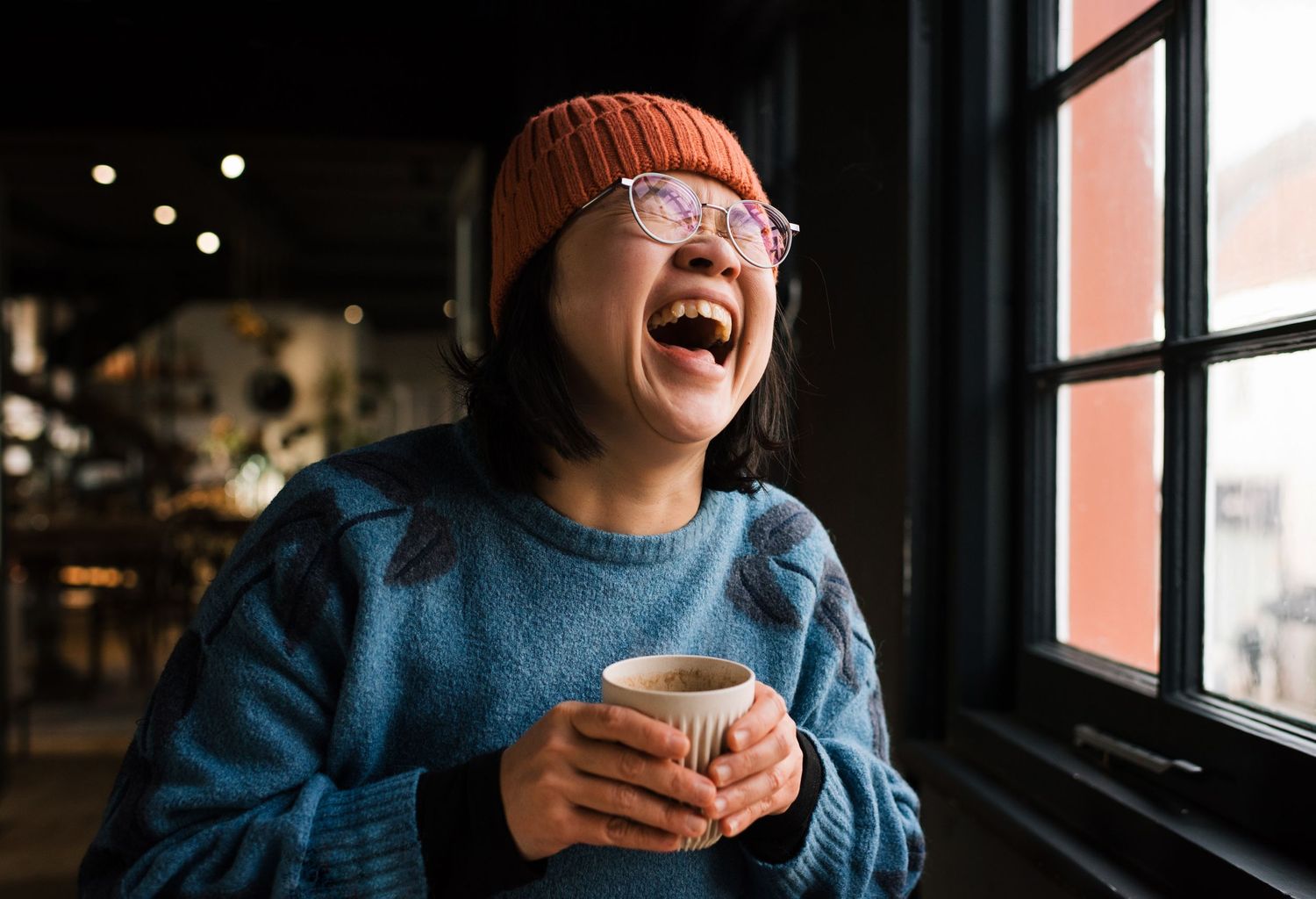 commercial lifestyle photography for a cafe in Stockholm, woman laughing whilst drinking coffee