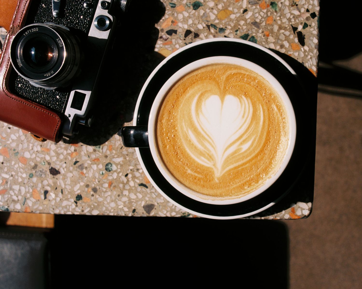 Cup of coffee on a table with an film camera. Commercial film photography analogue studio Stockholm