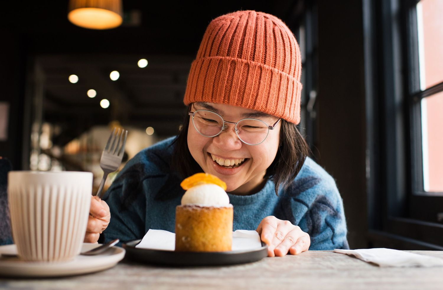 woman smiling at her cupcake in a cafe in Winchester UK. Commercial food photography