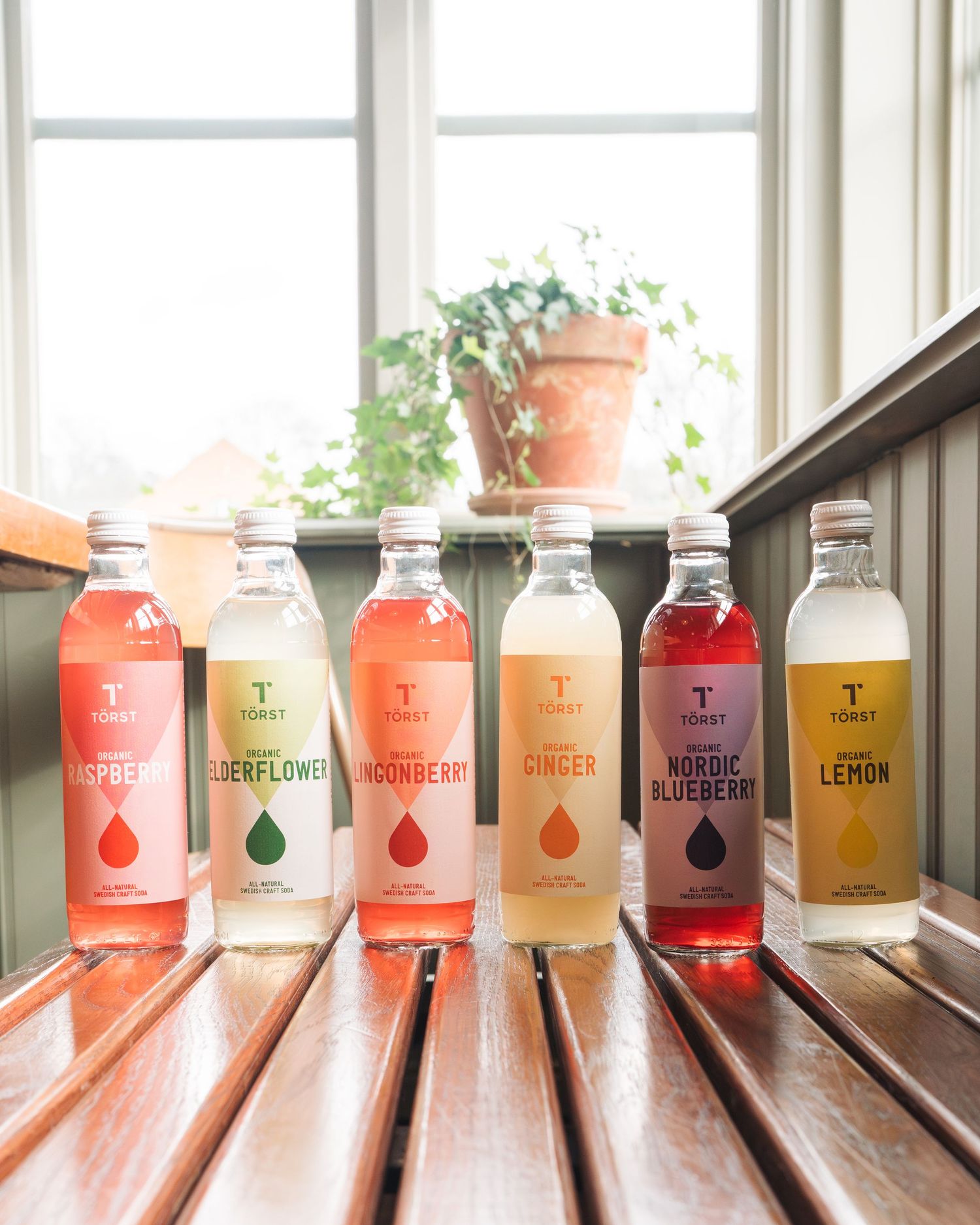 many flavours of Törst organic drinks lined up on a bench in a cafe for a commercial shoot in Stockholm.
