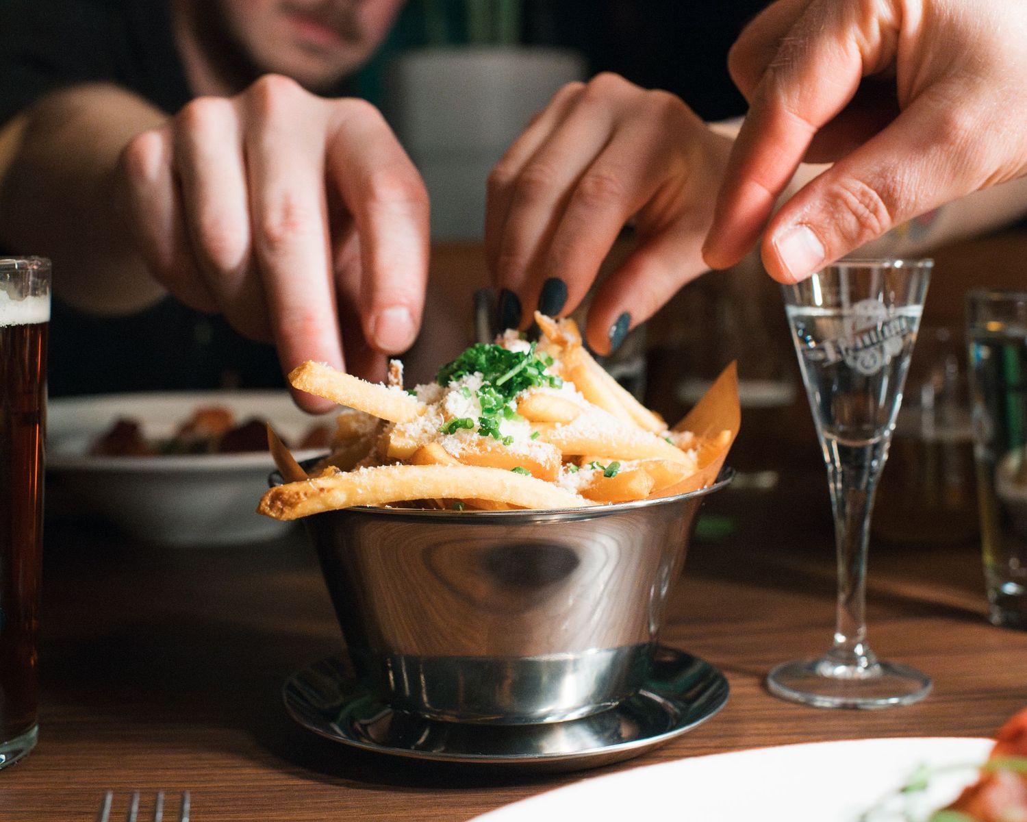 Vänner som delar pommes frites på en restaurang i Stockholm, fotograferade av en matfotograf i Sverige.