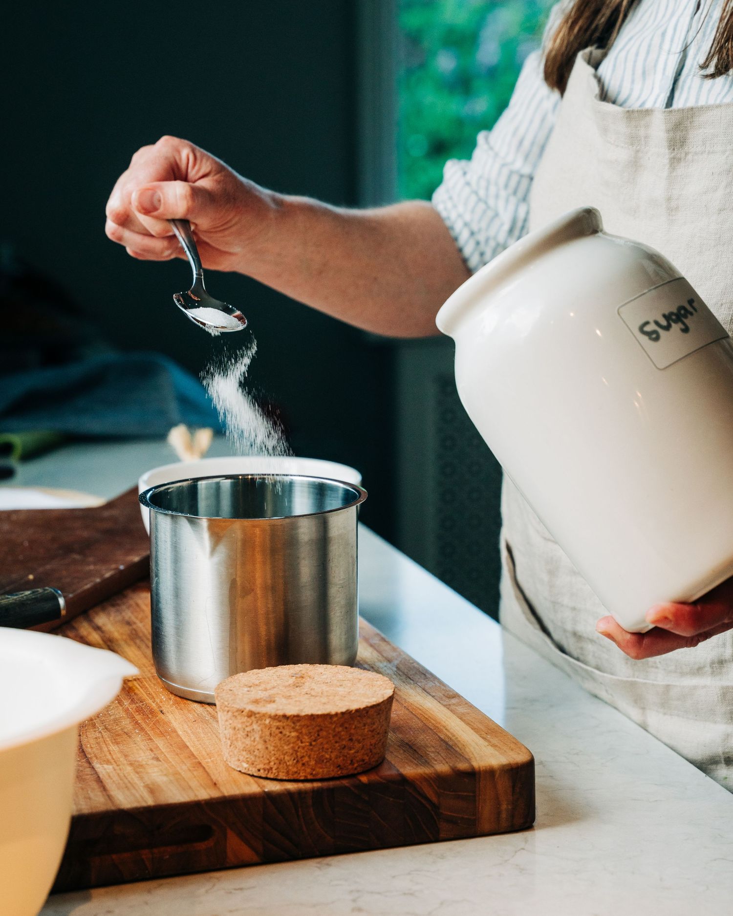 woman pouring sugar whilst home cooking for a cook book commercial food photography shoot in Sweden.