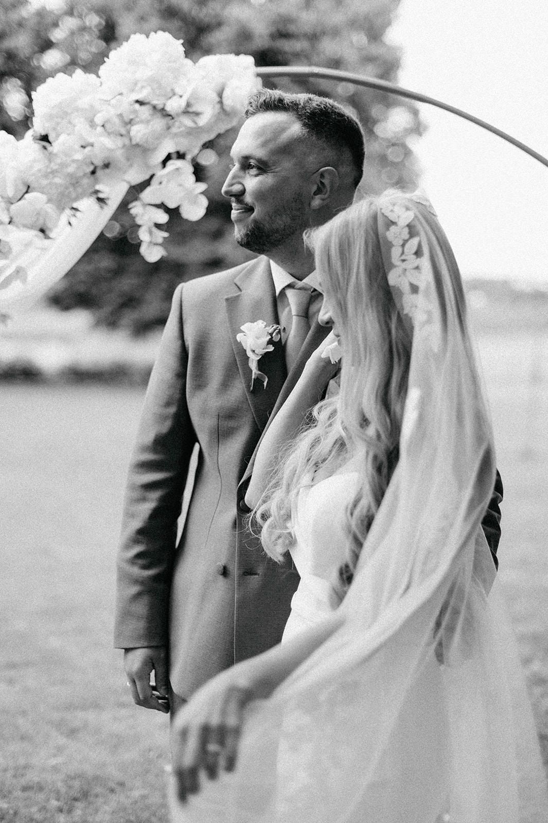 A romantic wedding photo series showing a couple in black and white with the bride wearing a flowing veil outdoors.