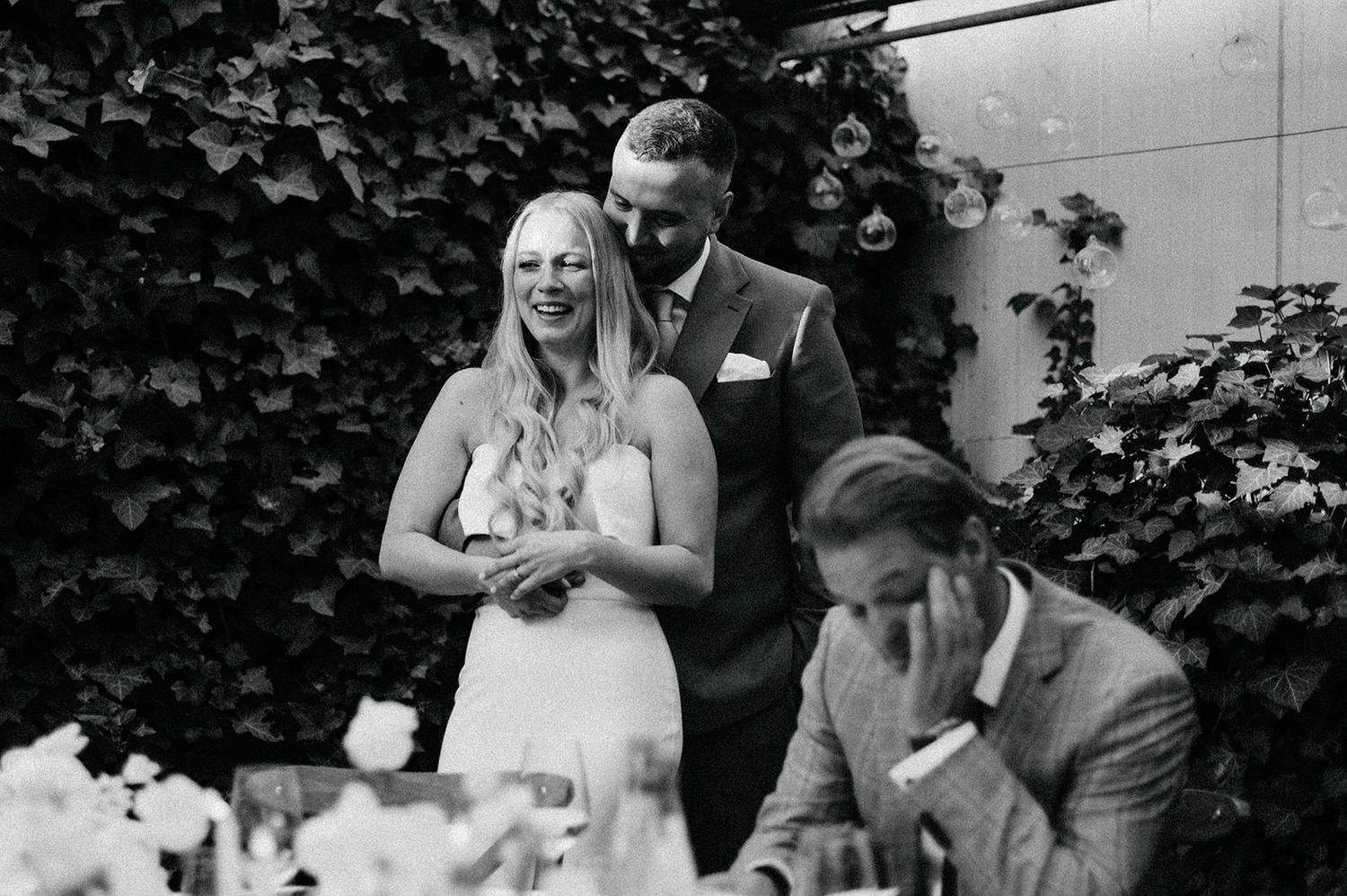 A series of black and white wedding photos arranged in a filmstrip style showing candid moments of celebration and joy.