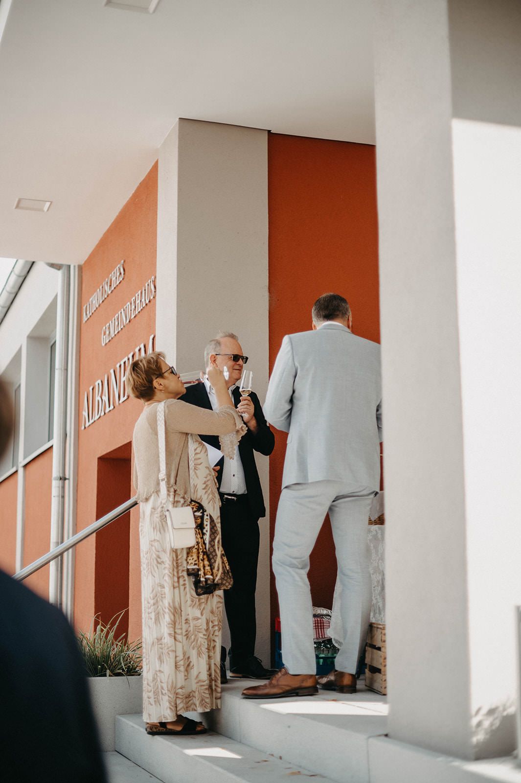 A sequence of four images showing people walking through a hallway with orange walls and white columns.