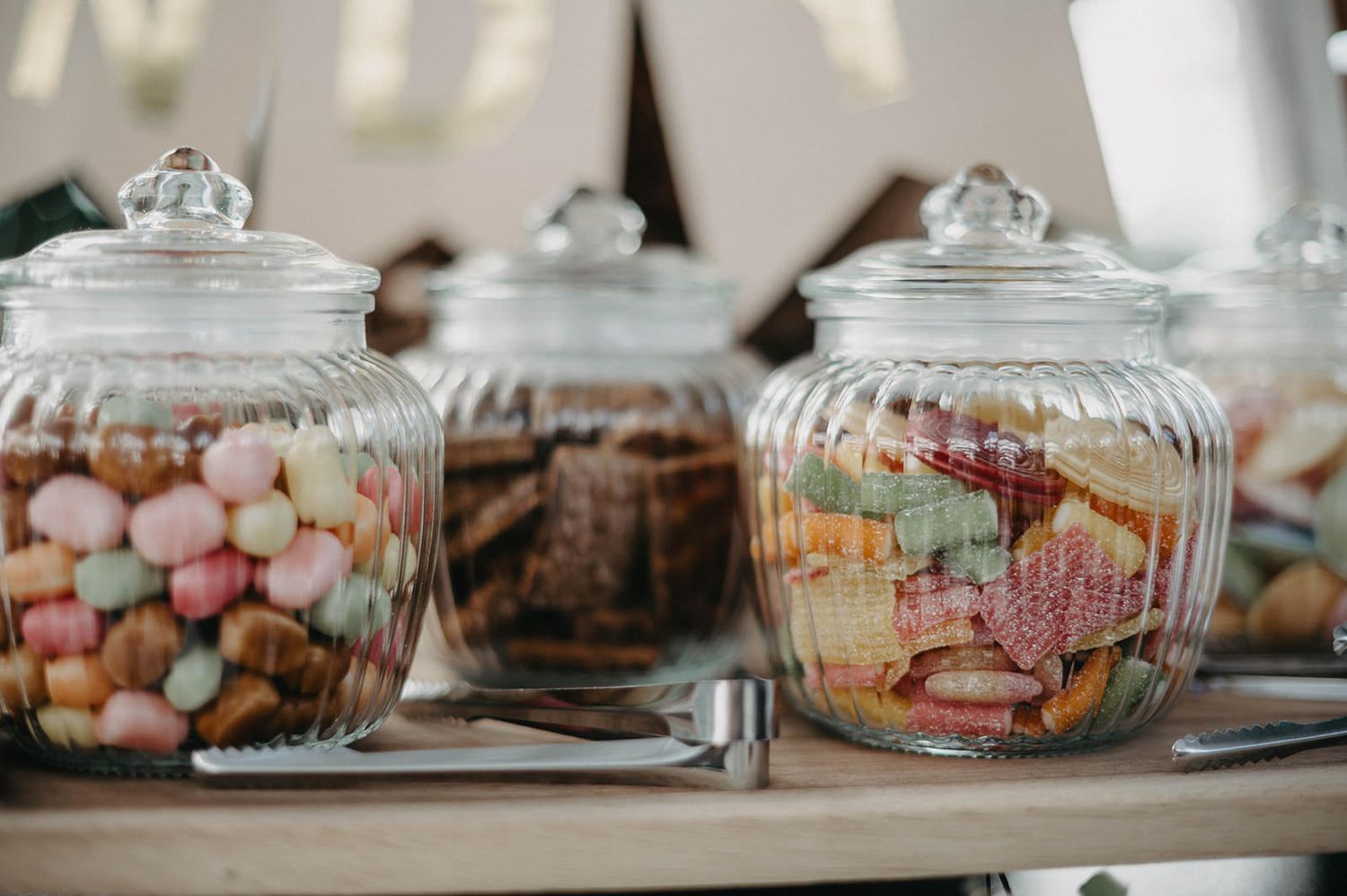 Glass apothecary jars filled with colorful candies and sweets displayed on a counter.