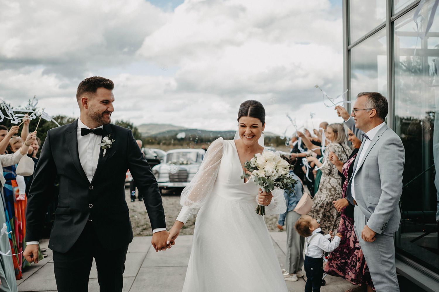 Wedding guests gather on a boat deck during a celebration with cloudy skies in the background.