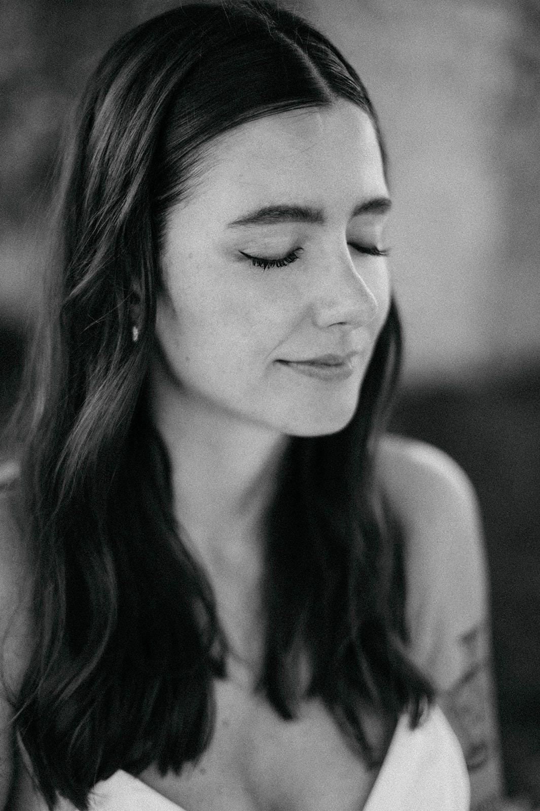 Black and white portrait of a woman with long dark hair and closed eyes in a serene pose.