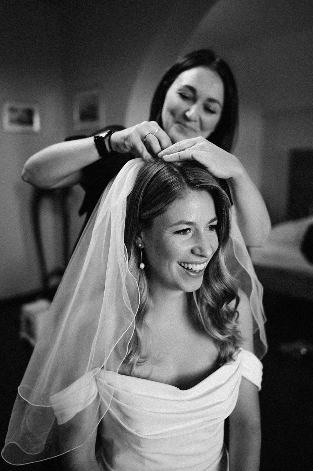 A bride smiles joyfully while getting ready in black and white candid wedding photography sequence.