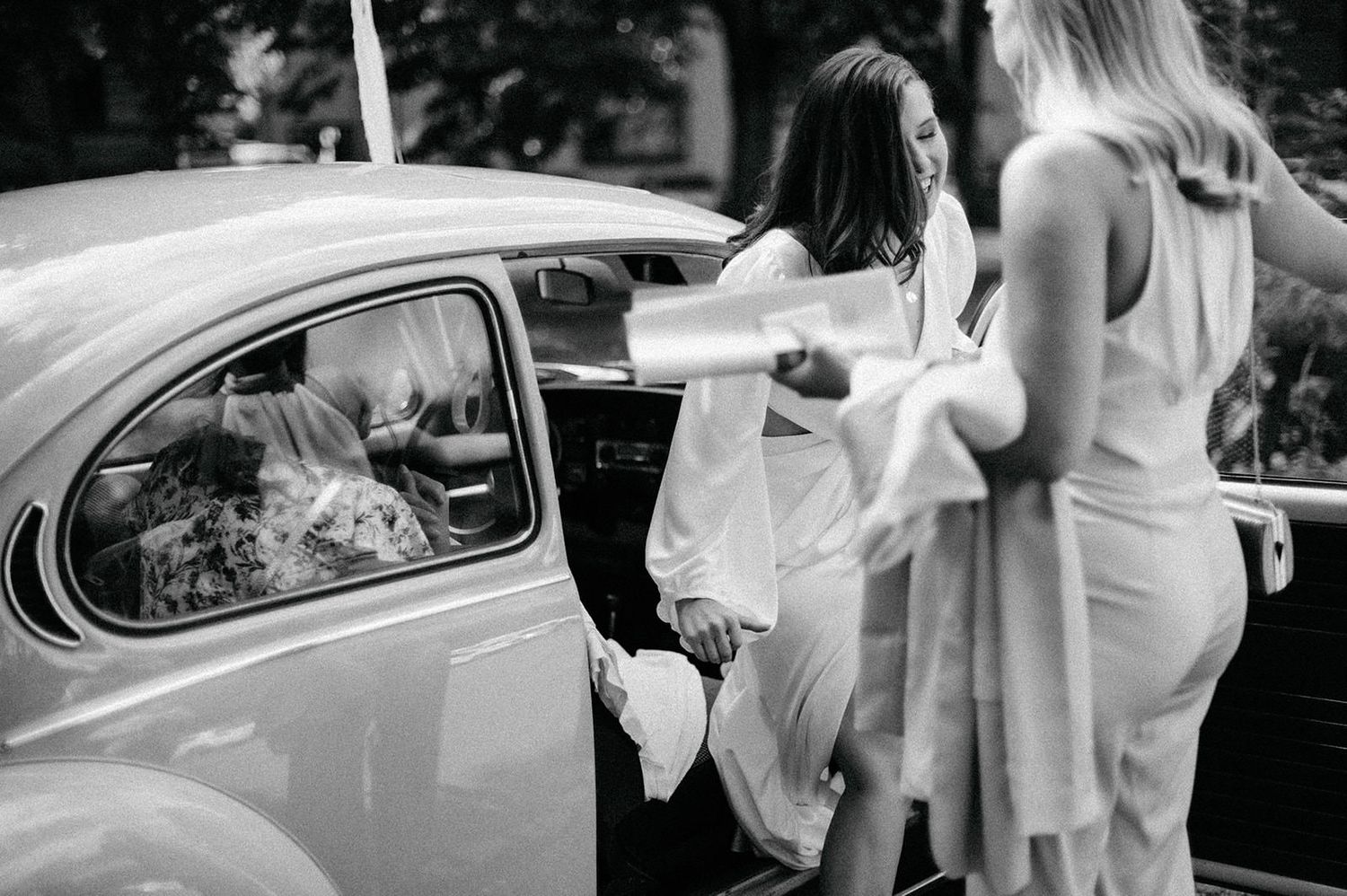 Sequence of black and white wedding photos showing bride and groom entering vintage car after ceremony.