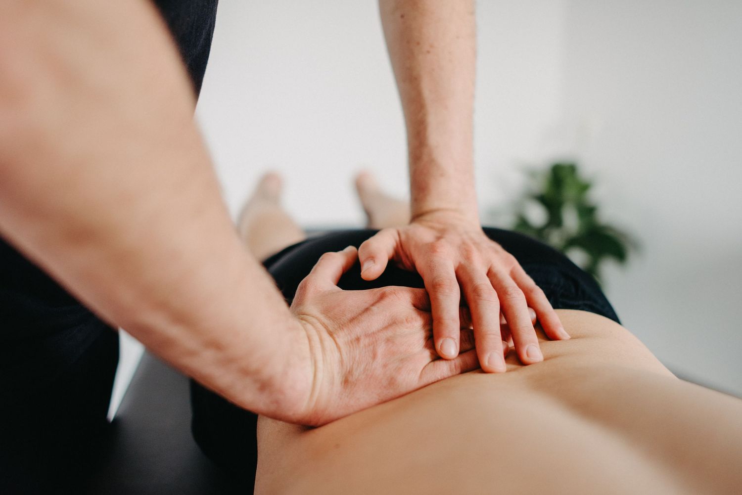 Close-up of hands performing therapeutic massage on back muscles.