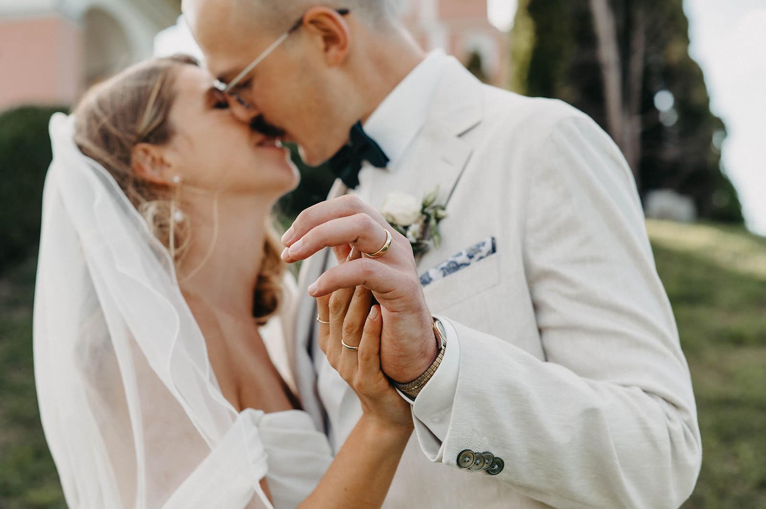 A series of intimate wedding photos showing tender moments between newlyweds against a pink building backdrop.