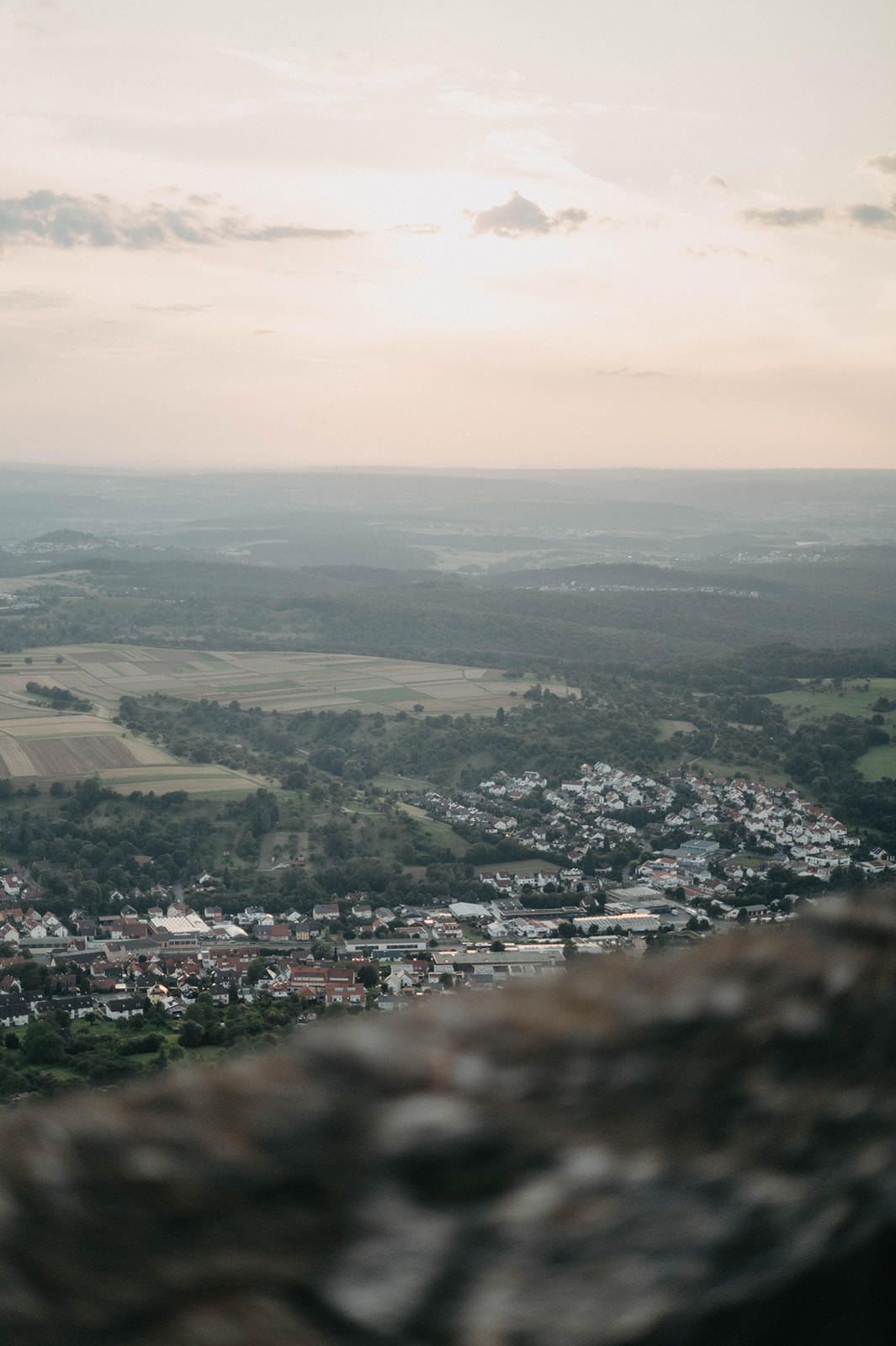 Panoramic aerial view of a small town nestled in rolling hills during sunset with moody overcast skies.