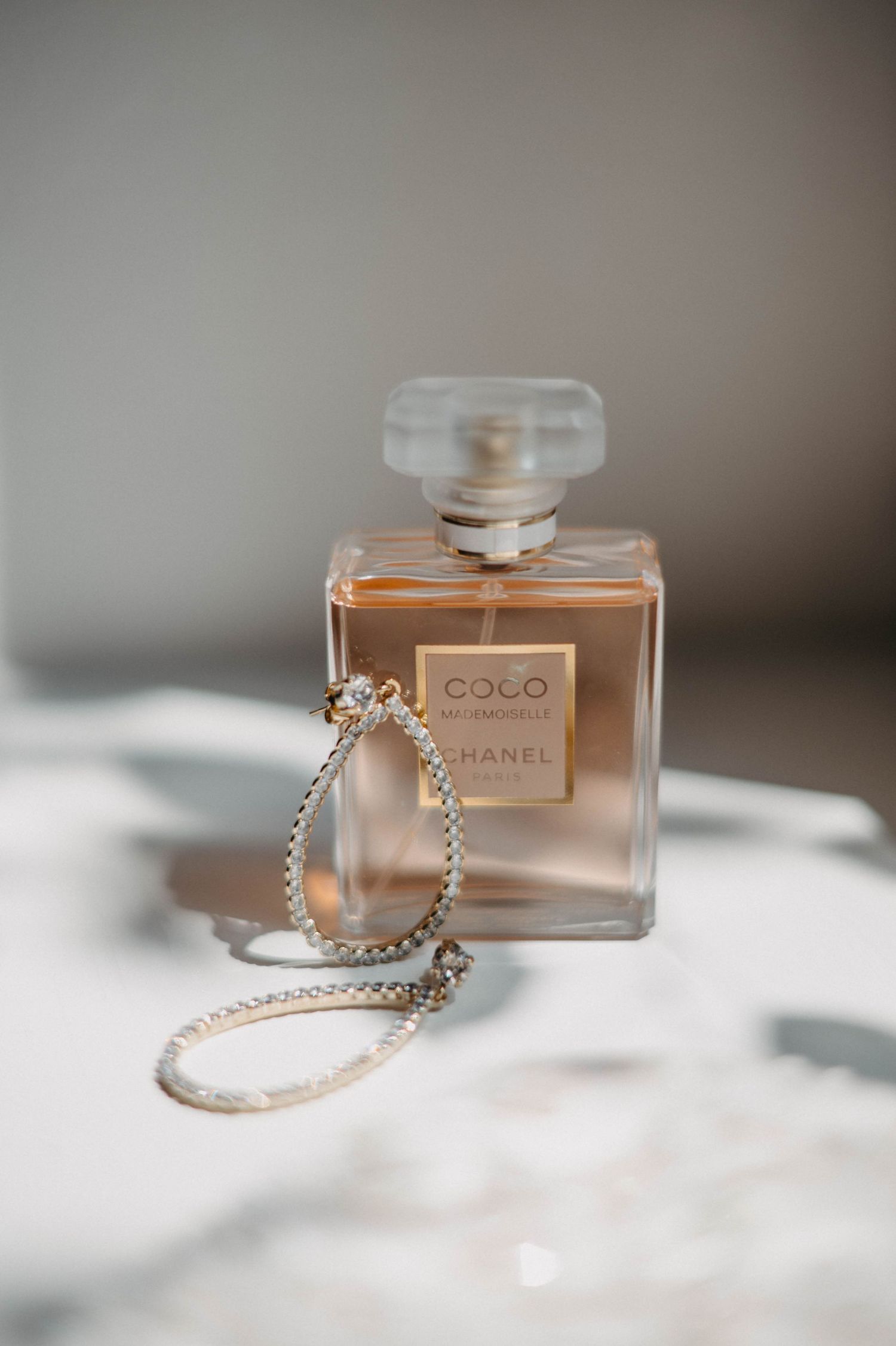 Elegant perfume bottles and jewelry arranged on white surface with soft shadows.