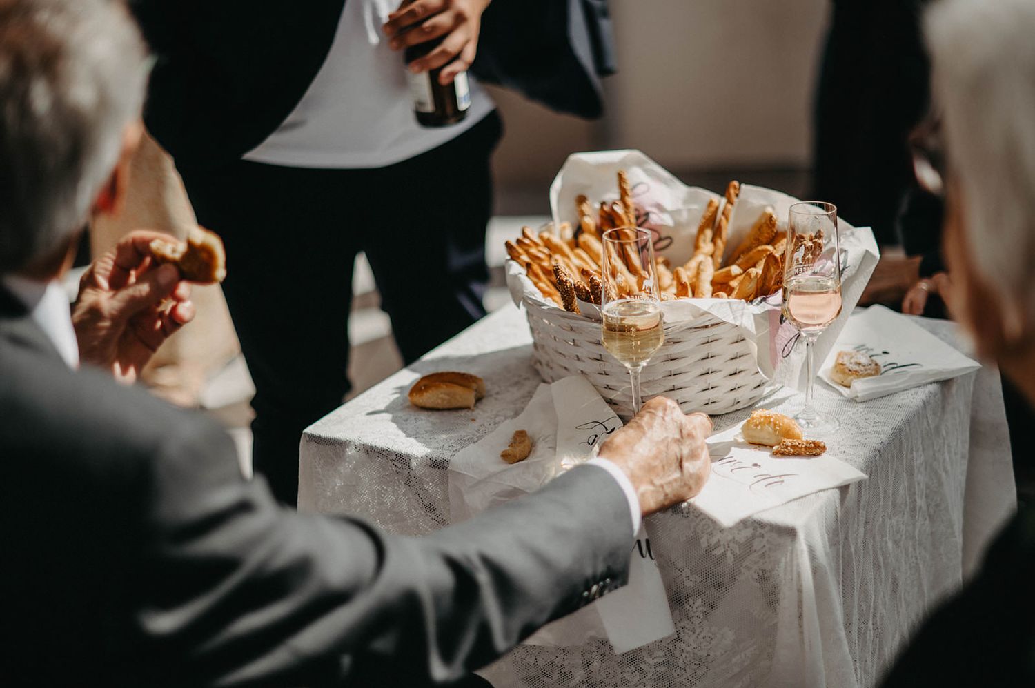 Hands reaching for crispy french fries served on white paper at a casual dining gathering.