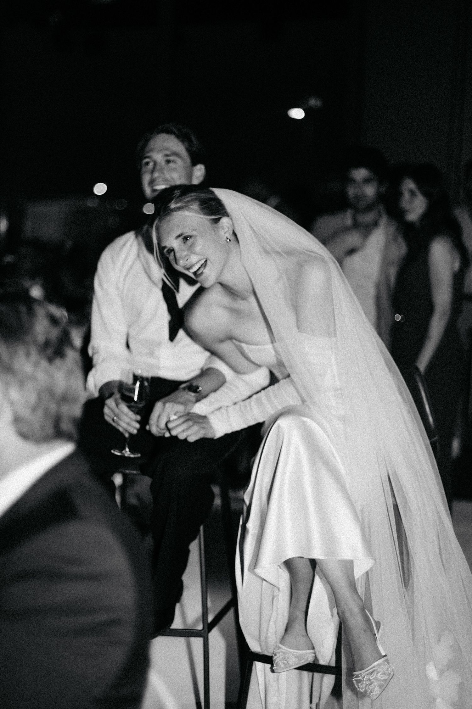 Black and white candid reception moment with elegant white wedding dress.