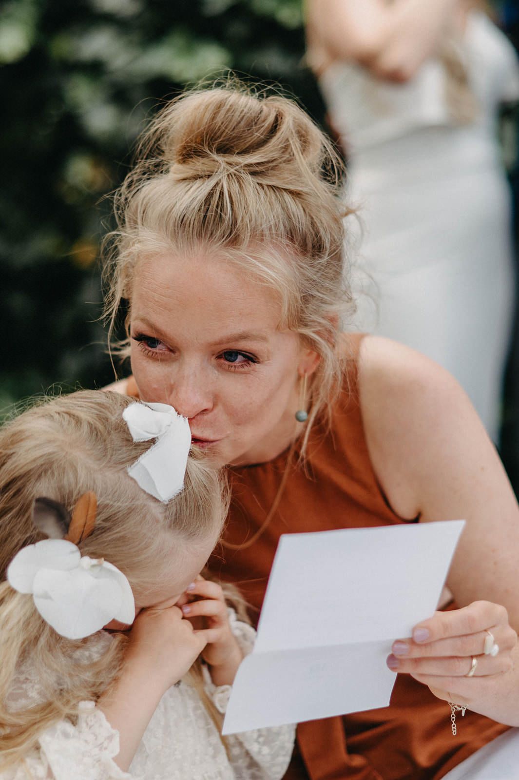 An emotional moment captured as someone in a rust-colored dress reads a letter while comforting a child in white.