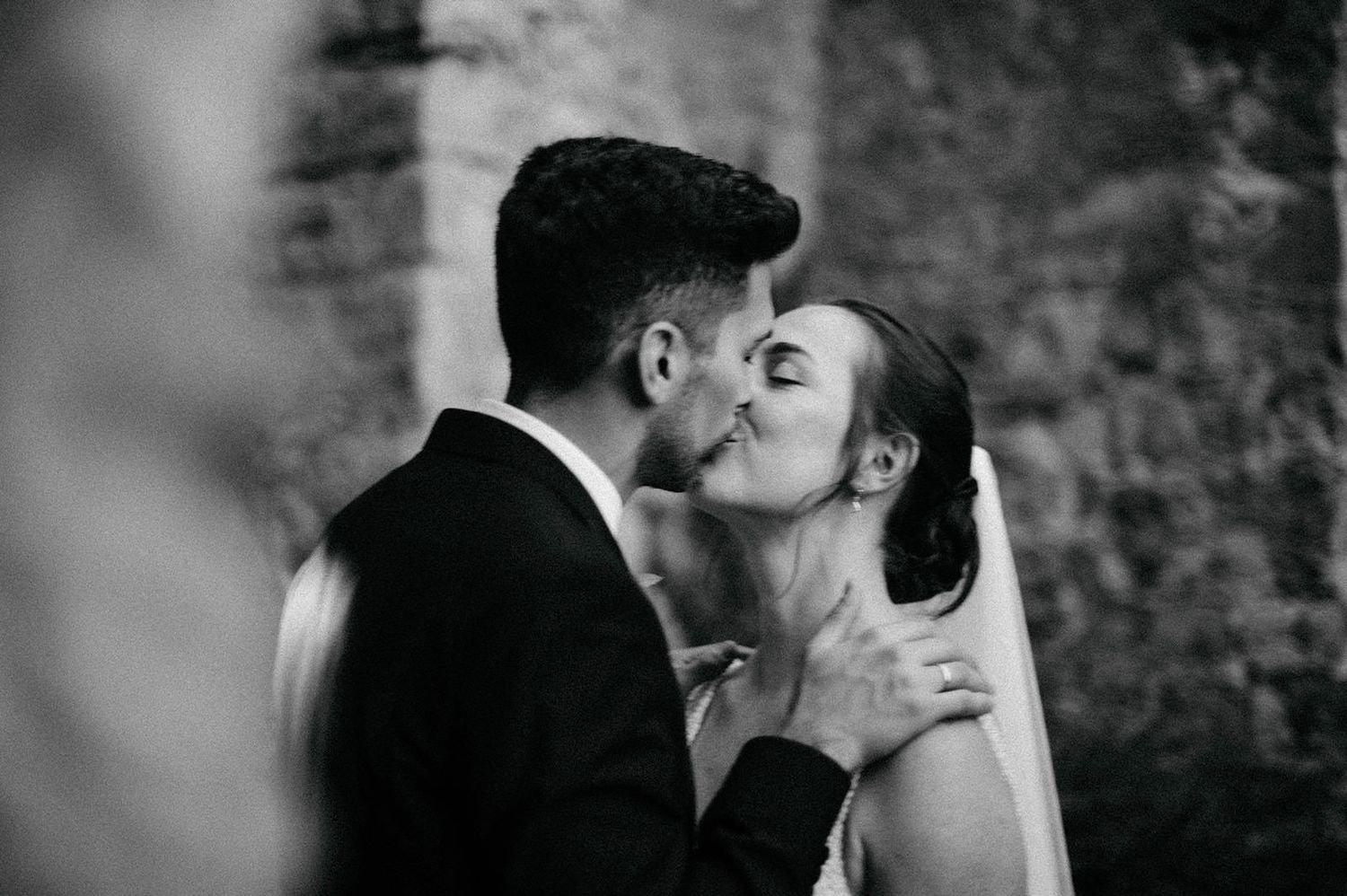 Black and white photo series showing a romantic kiss between a couple in formal wedding attire.