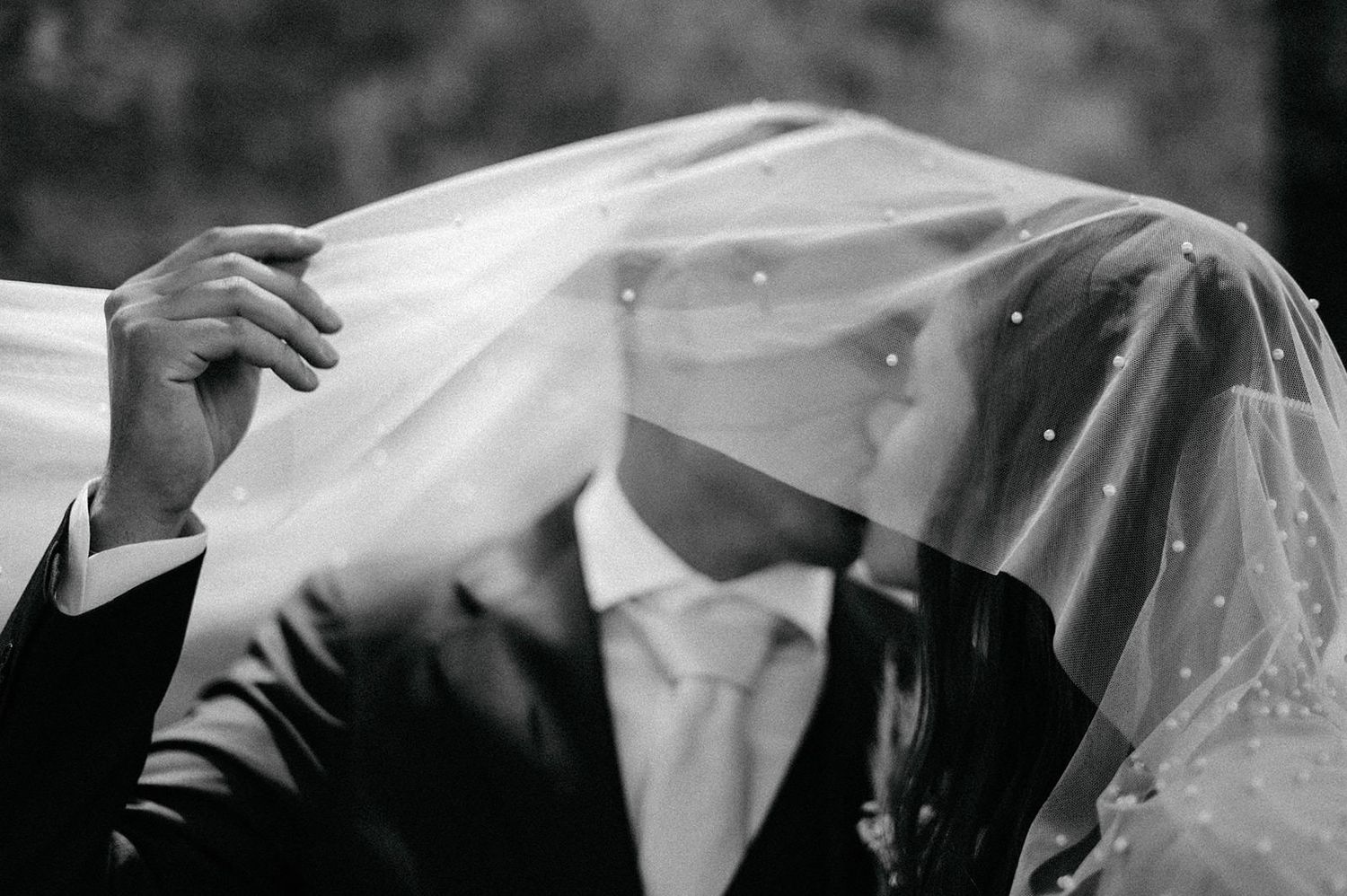 Elegant black and white wedding photo series showing close-up details of bridal veil and hands during ceremony.