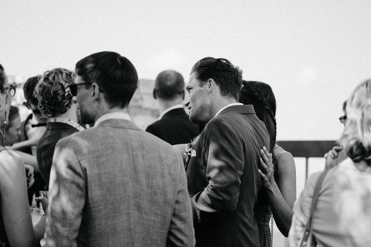 Black and white candid photo of people mingling at a social gathering.