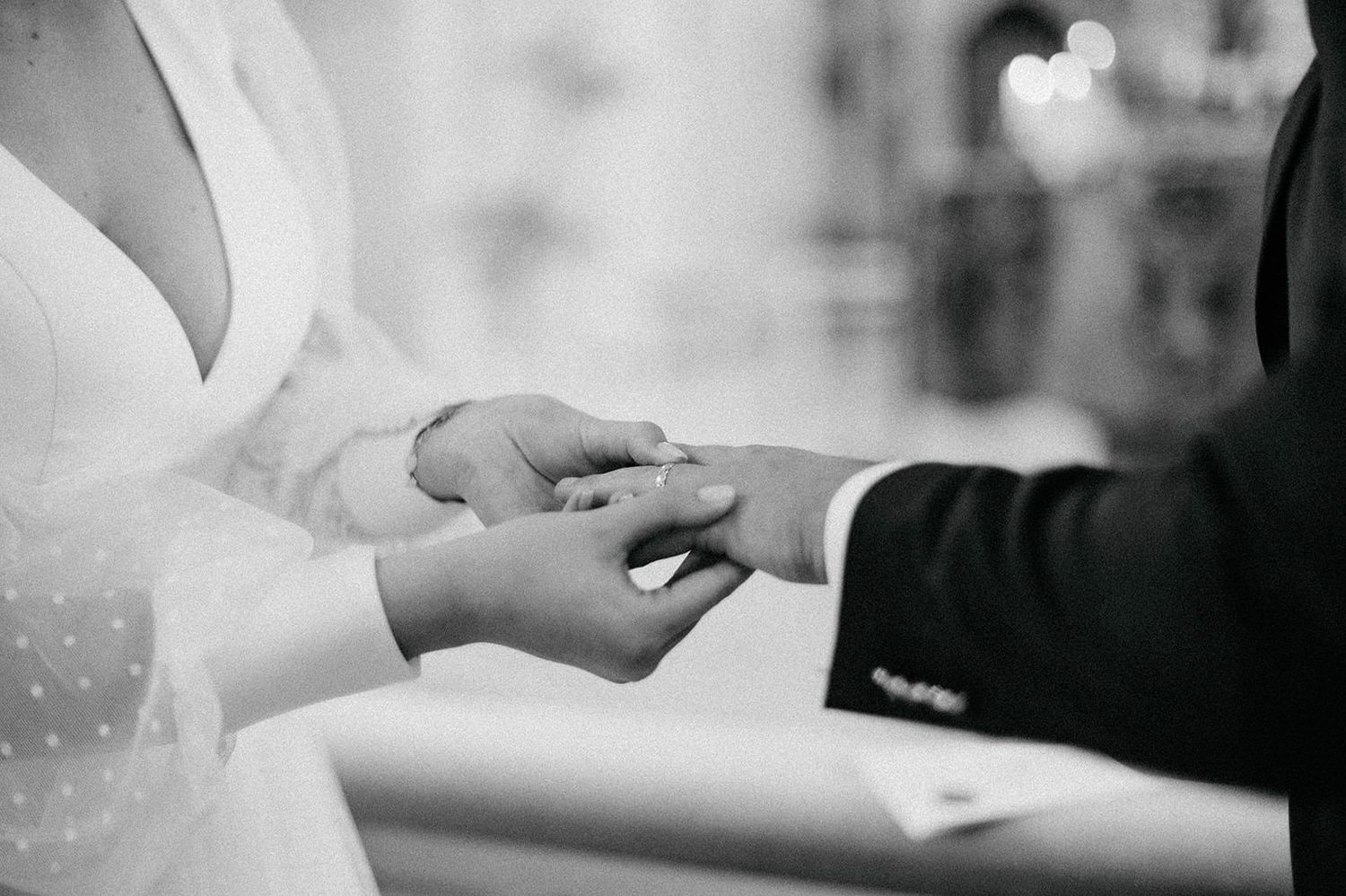 Black and white photo of a couple exchanging rings during a wedding ceremony.