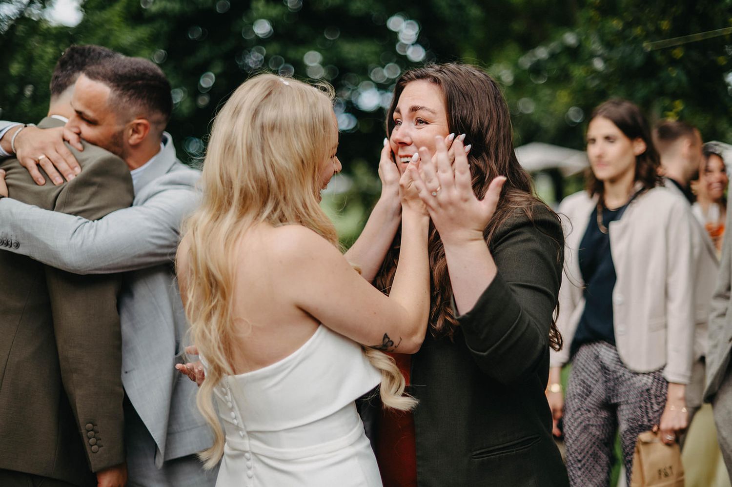 Wedding guests dance and celebrate together during an outdoor reception in a garden setting.
