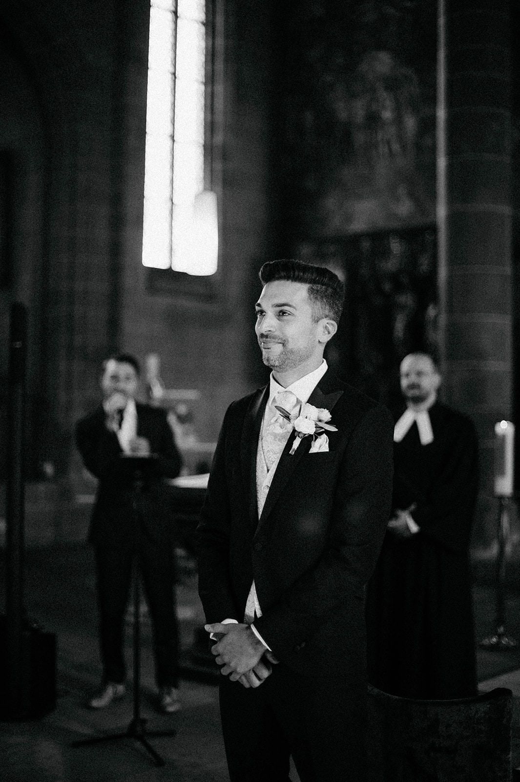 A black and white photo series shows a groom and groomsmen in formal attire at a wedding venue.