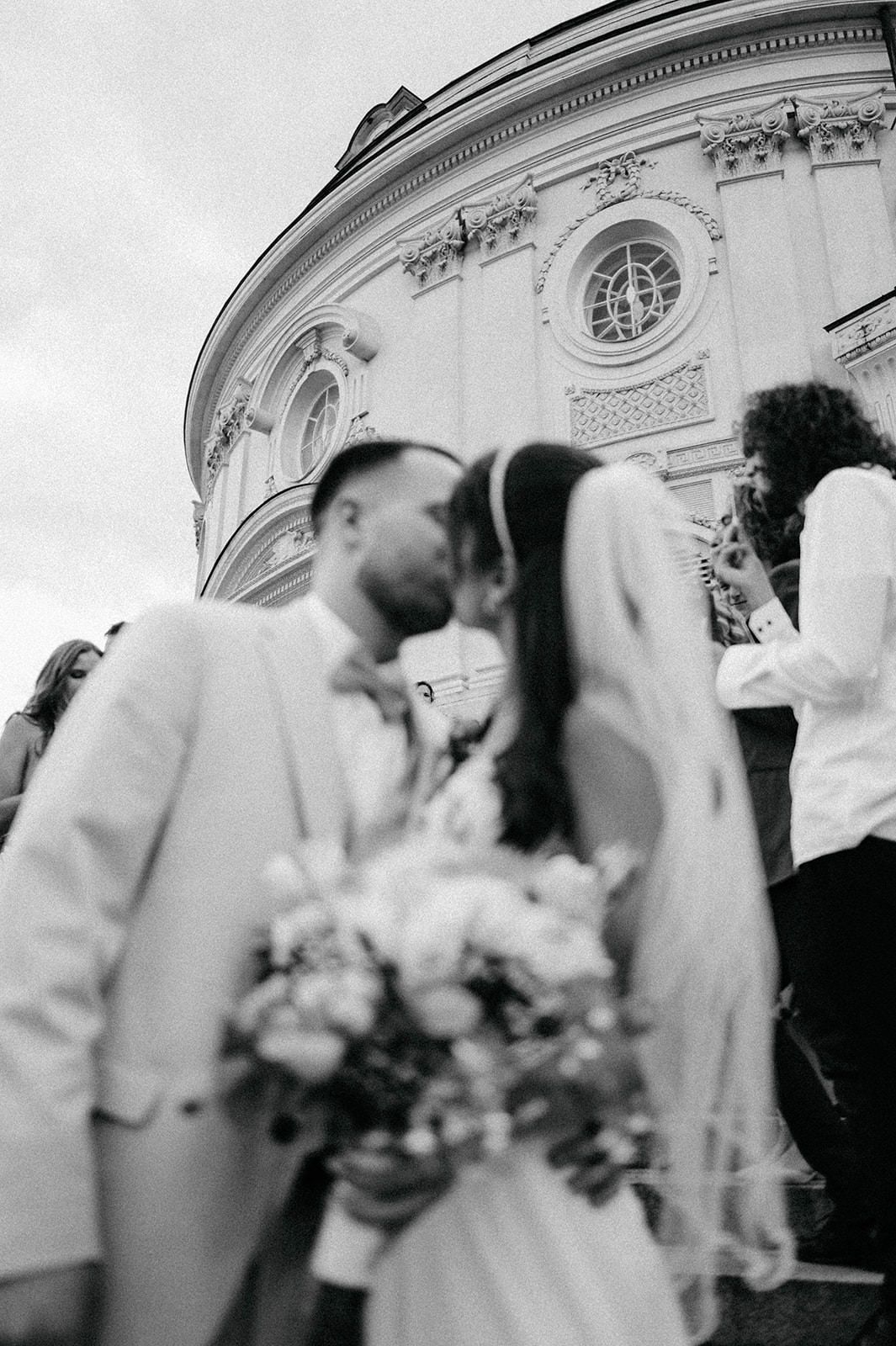 A sequence of blurred black and white wedding photos showing couples embracing outside an ornate building.