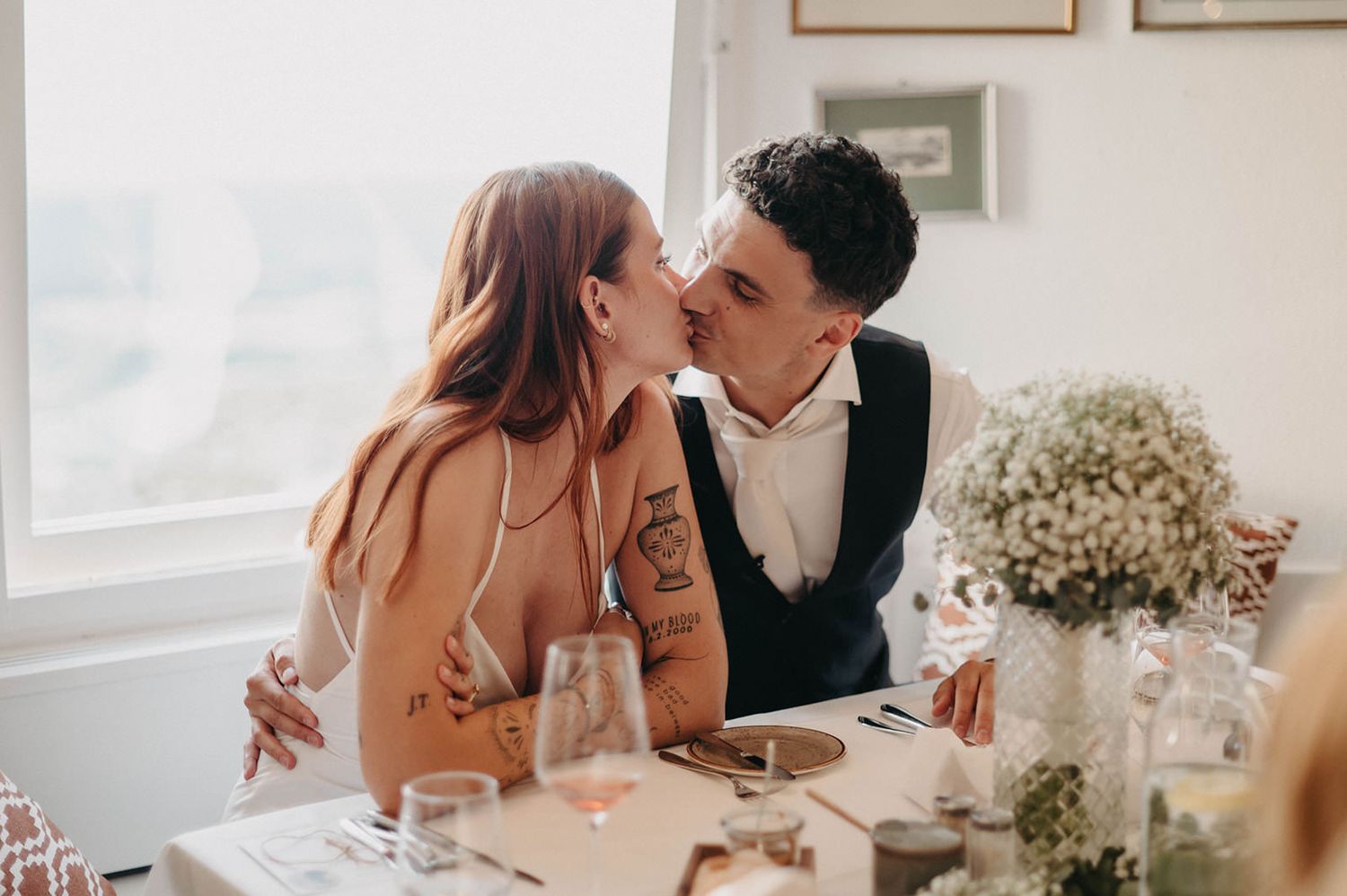 A romantic wedding scene with couples sharing intimate moments surrounded by white floral decorations.
