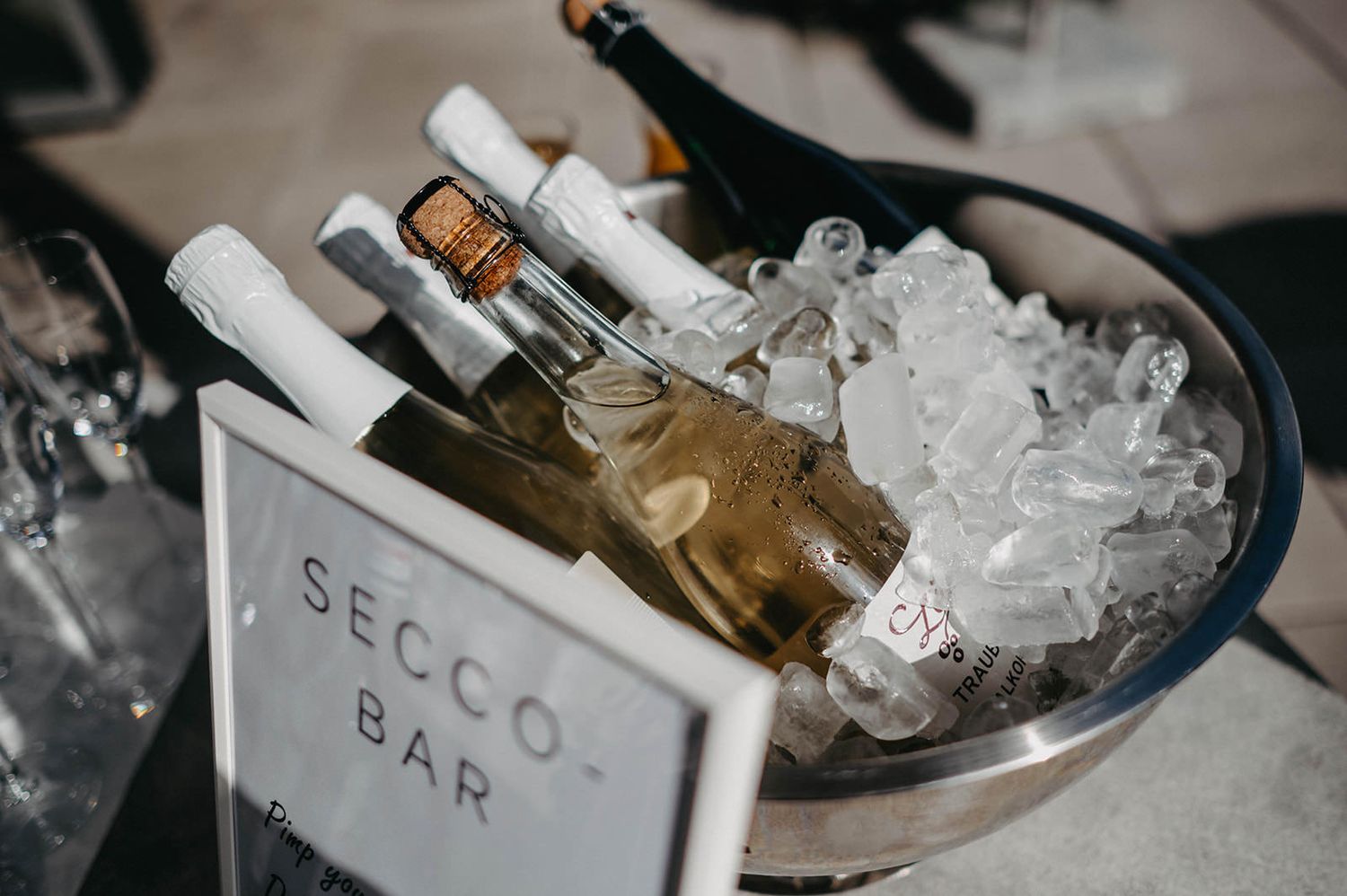 Bottles of champagne and wine chilling in ice buckets at an outdoor event.