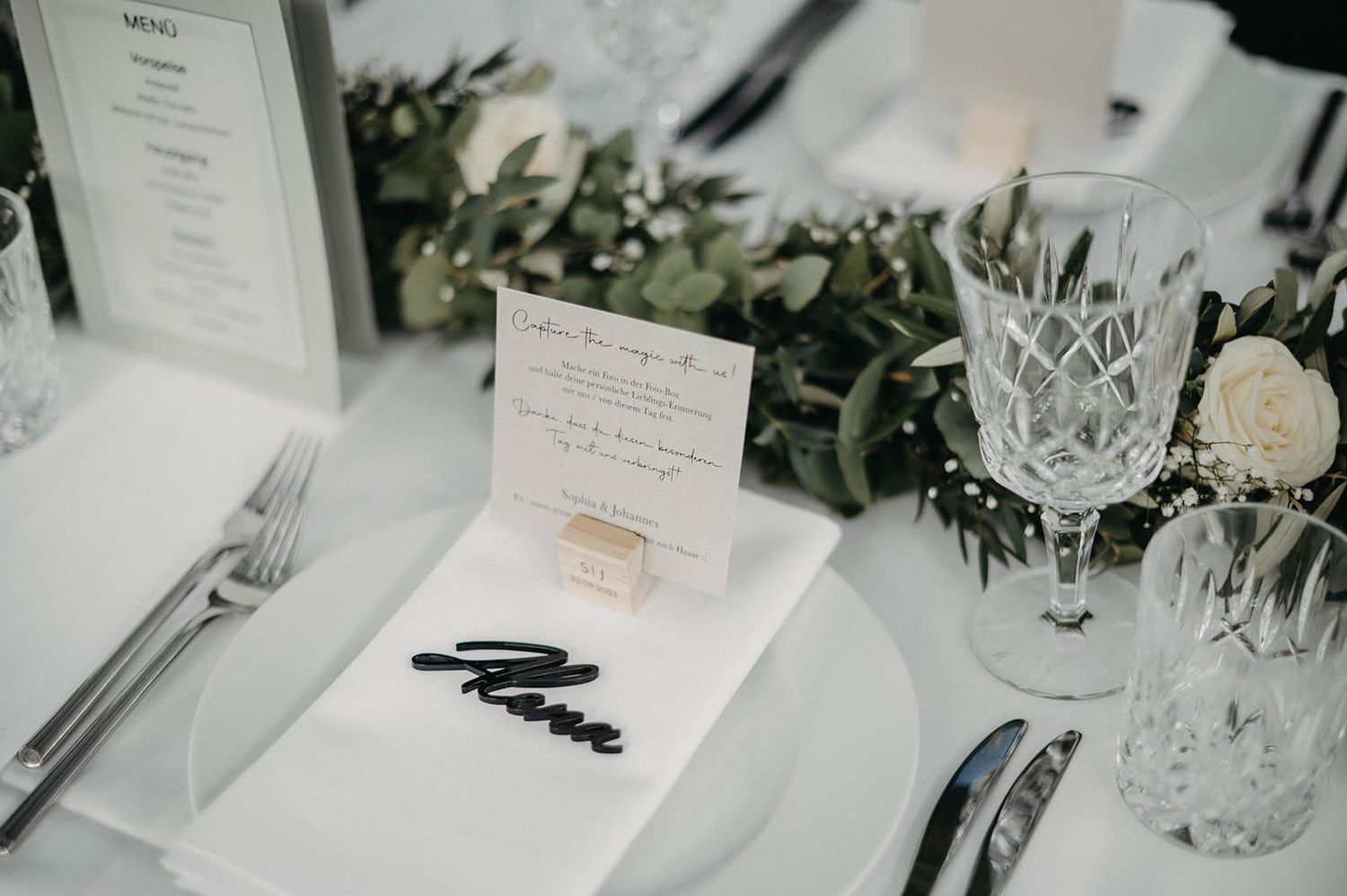 Elegant wedding reception table settings with white menus, crystal glassware, and delicate floral centerpieces.
