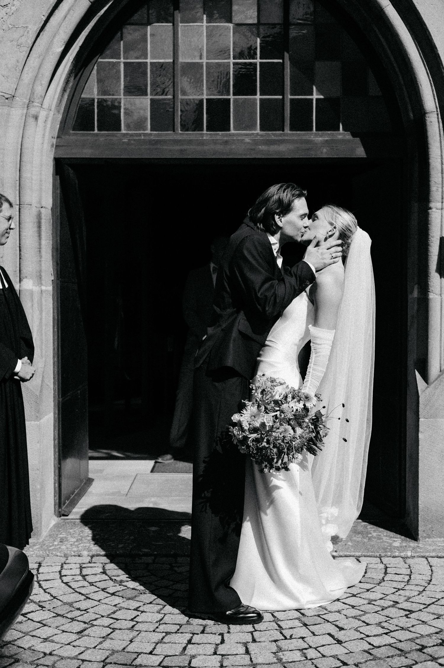 A series of romantic black and white wedding photos showing a couple kissing under stone archways.